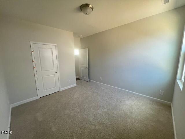 Spacious bedroom featuring beige walls, plush carpet, white doors to closet and bath, in Davidson Homes The Adalynn A, Lillington, NC