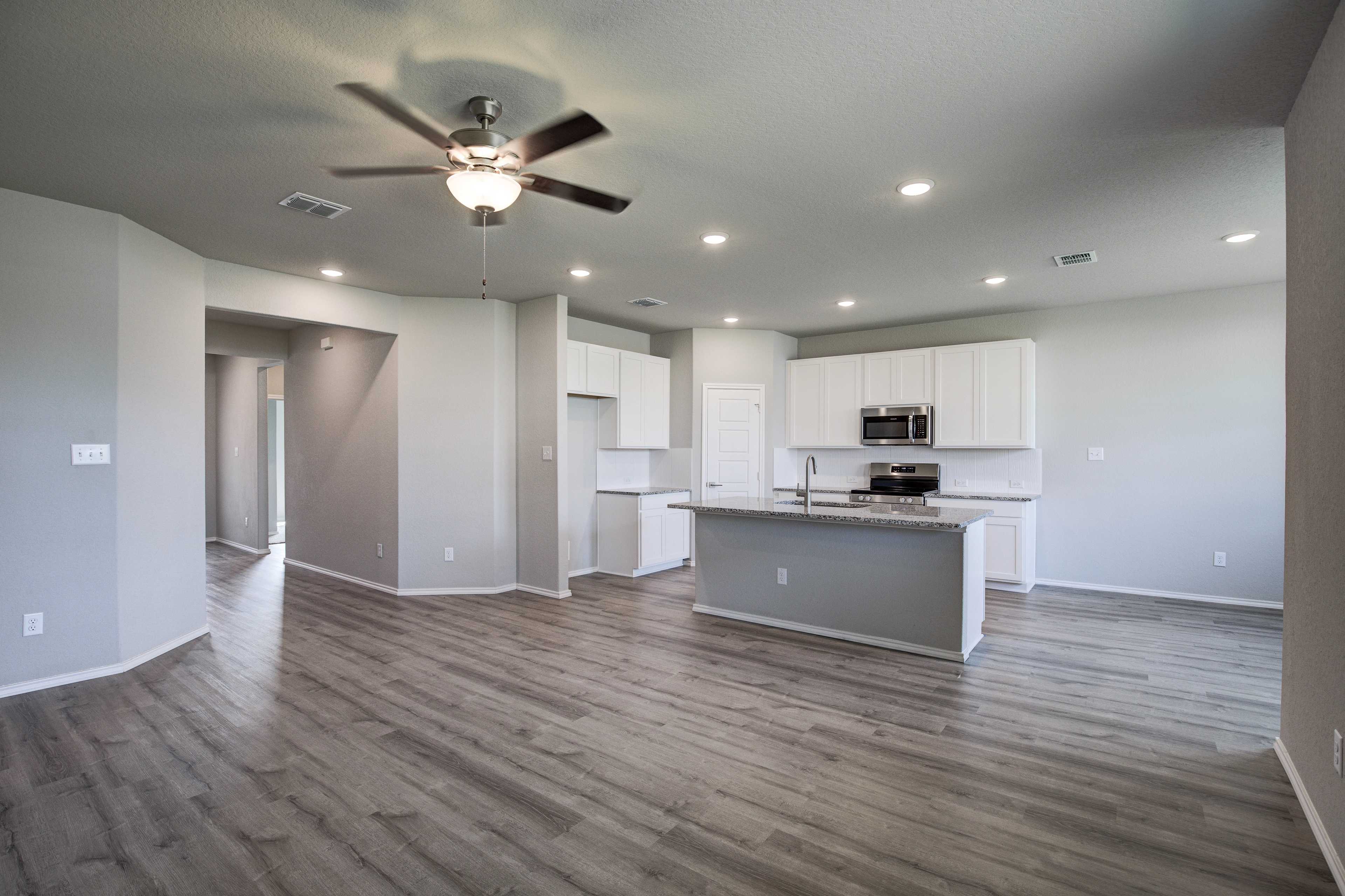 Spacious open-concept kitchen in The Asheville by Davidson Homes with white cabinets, large island, stainless appliances, and hardwood floors