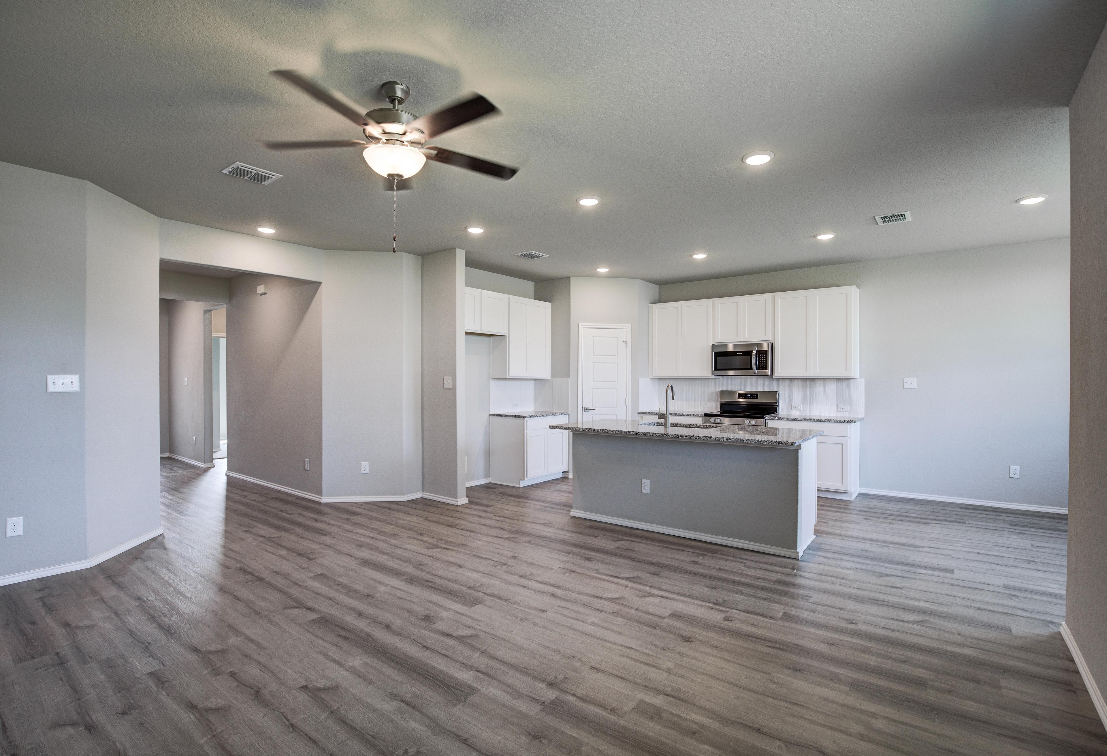 Spacious open-concept kitchen in The Asheville home with white cabinets, large island, stainless steel appliances, and hardwood floors