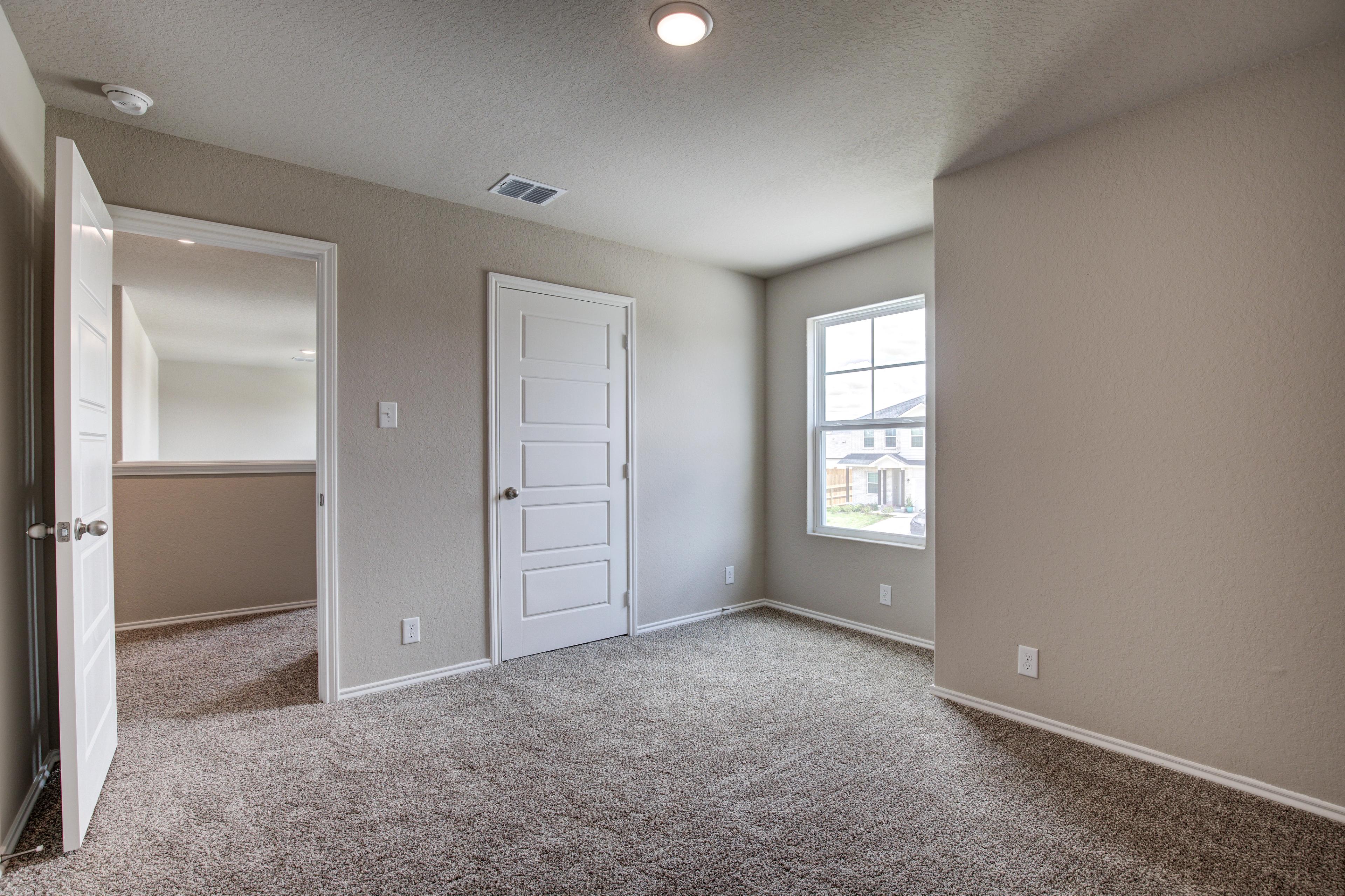Second-floor bedroom in The Murray G home with beige walls, neutral carpet, double doors, and window view