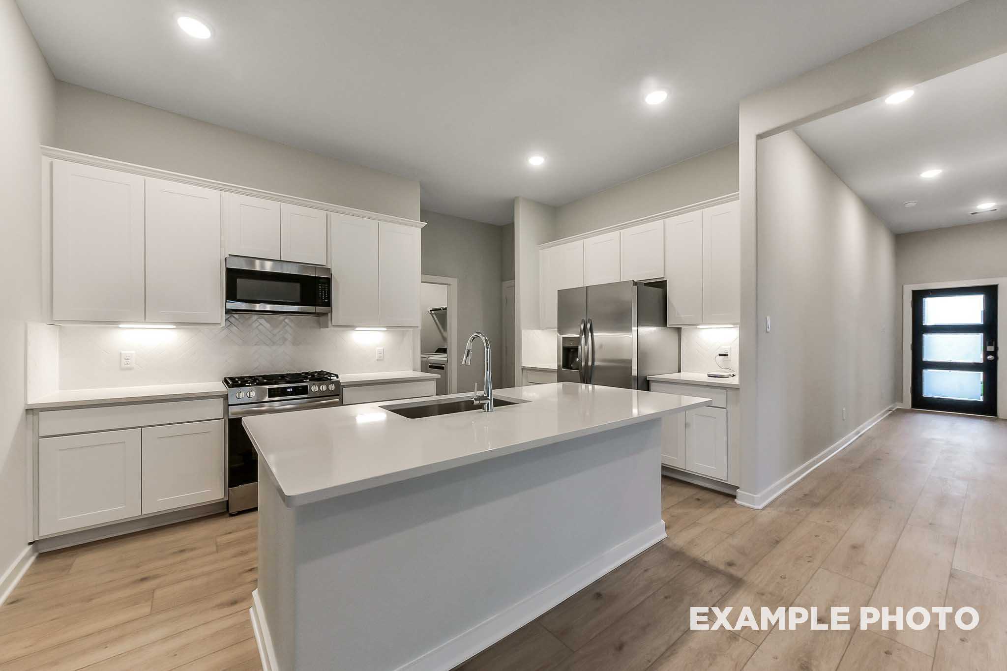 Spacious modern kitchen in The Laguna B with white shaker cabinets, quartz island sink, stainless steel appliances, open layout