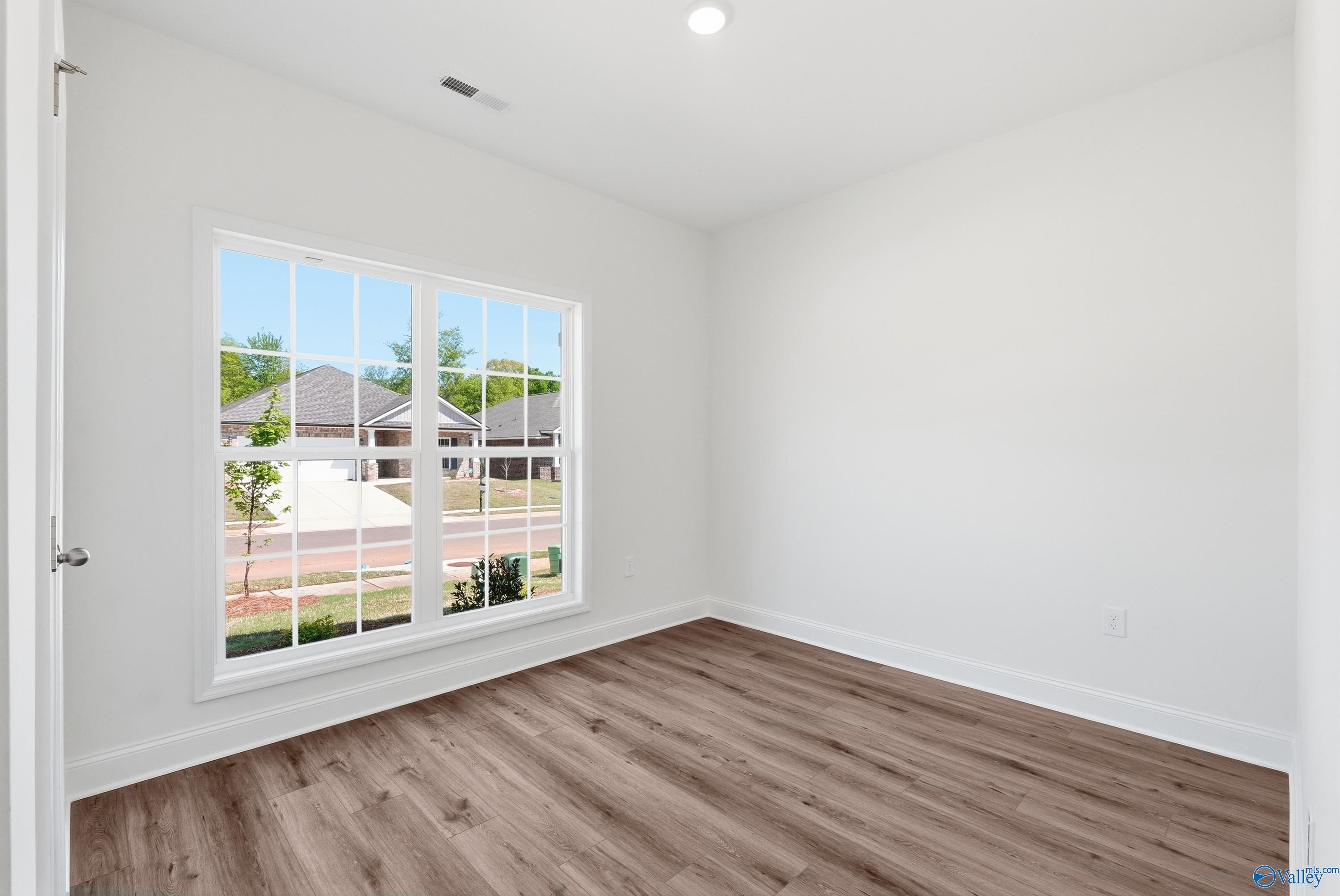 Bright bedroom with wood-look flooring and natural light in The Asheville floor plan at Jaguar Hills, Huntsville, Alabama.
