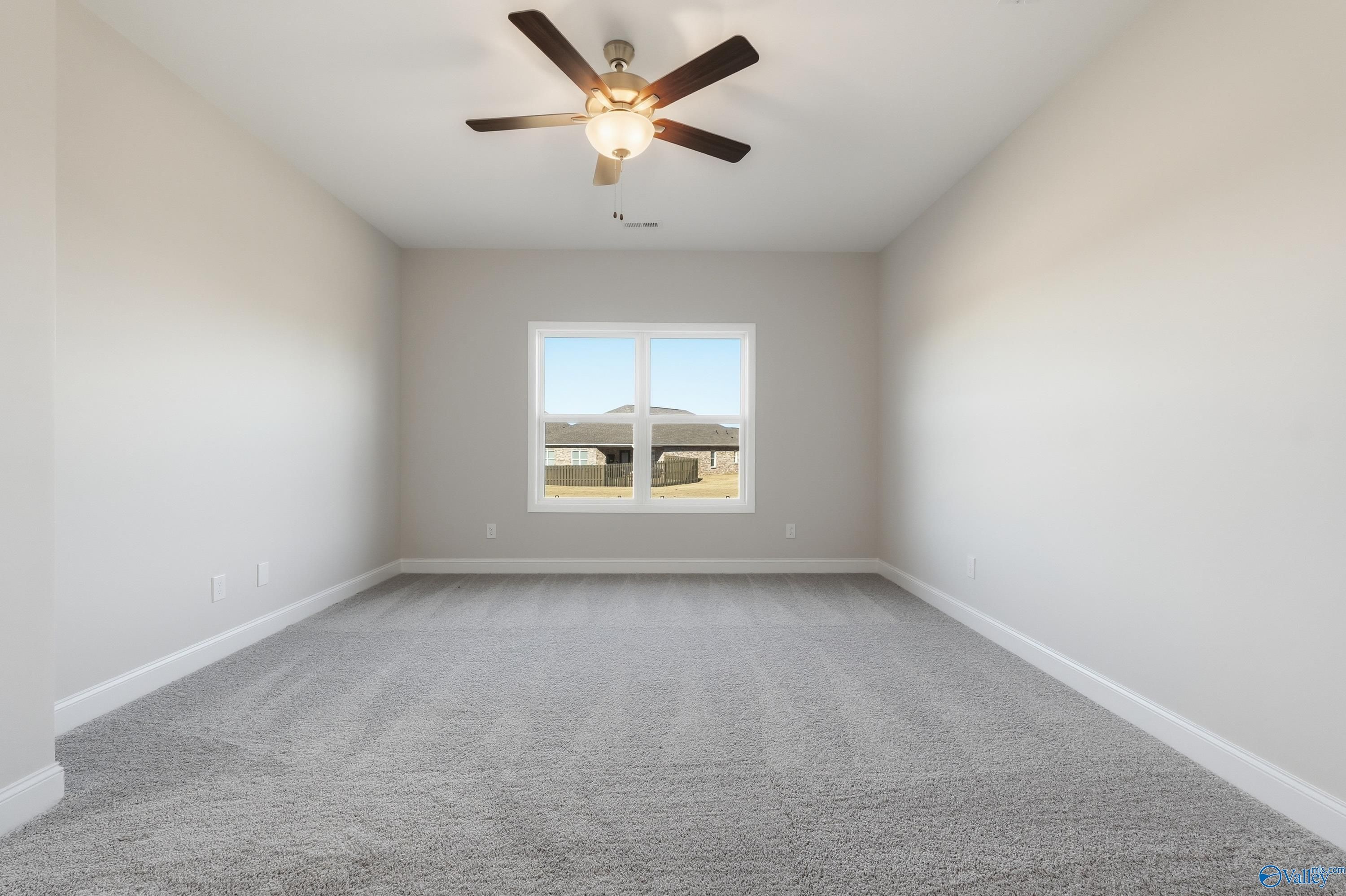 Bright secondary bedroom featuring ceiling fan, large window, and neutral walls in Davidson Homes The Everett, Harvest, Alabama
