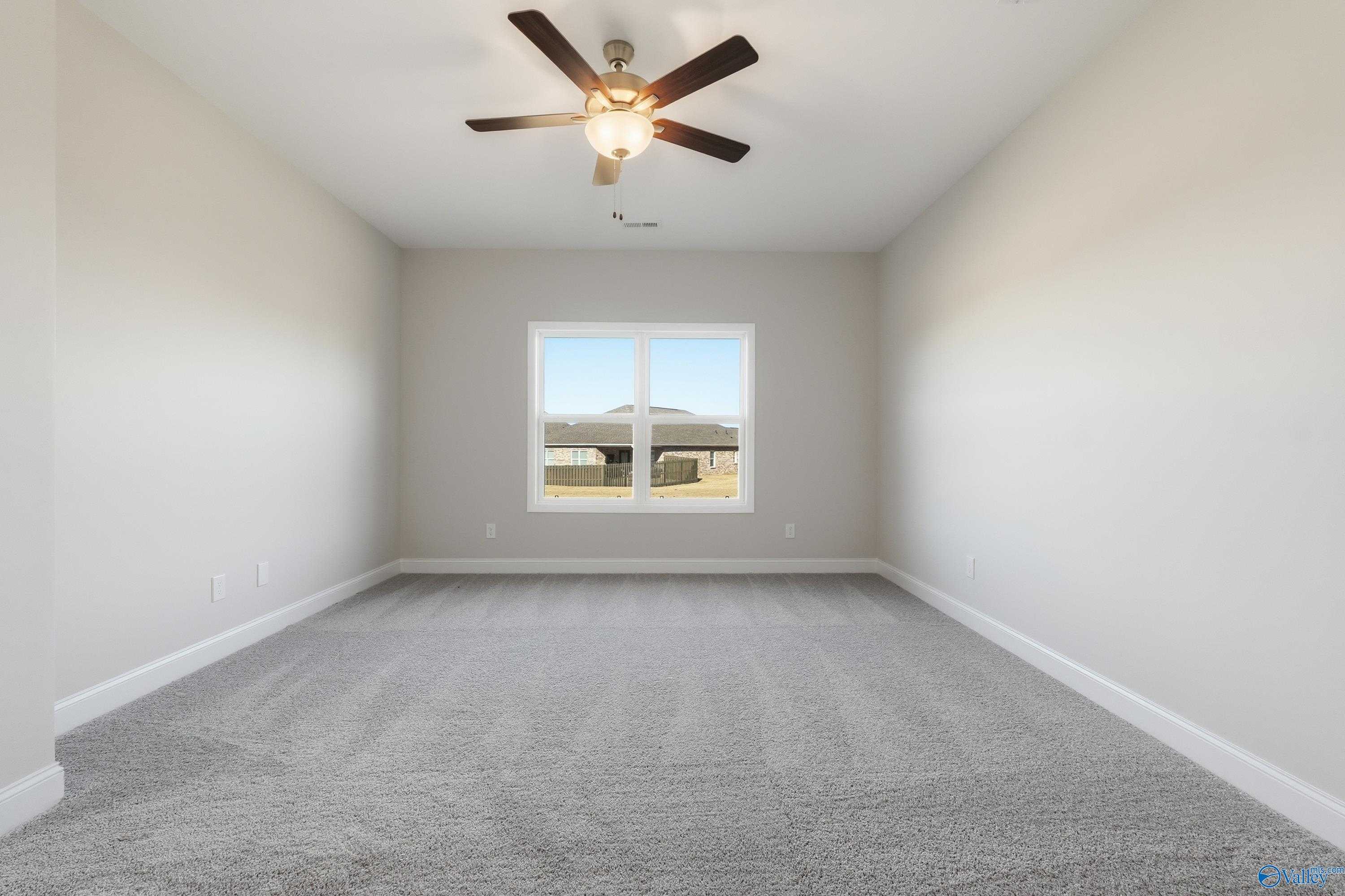 Bright secondary bedroom featuring ceiling fan, large window, and neutral walls in Davidson Homes The Everett, Harvest, Alabama