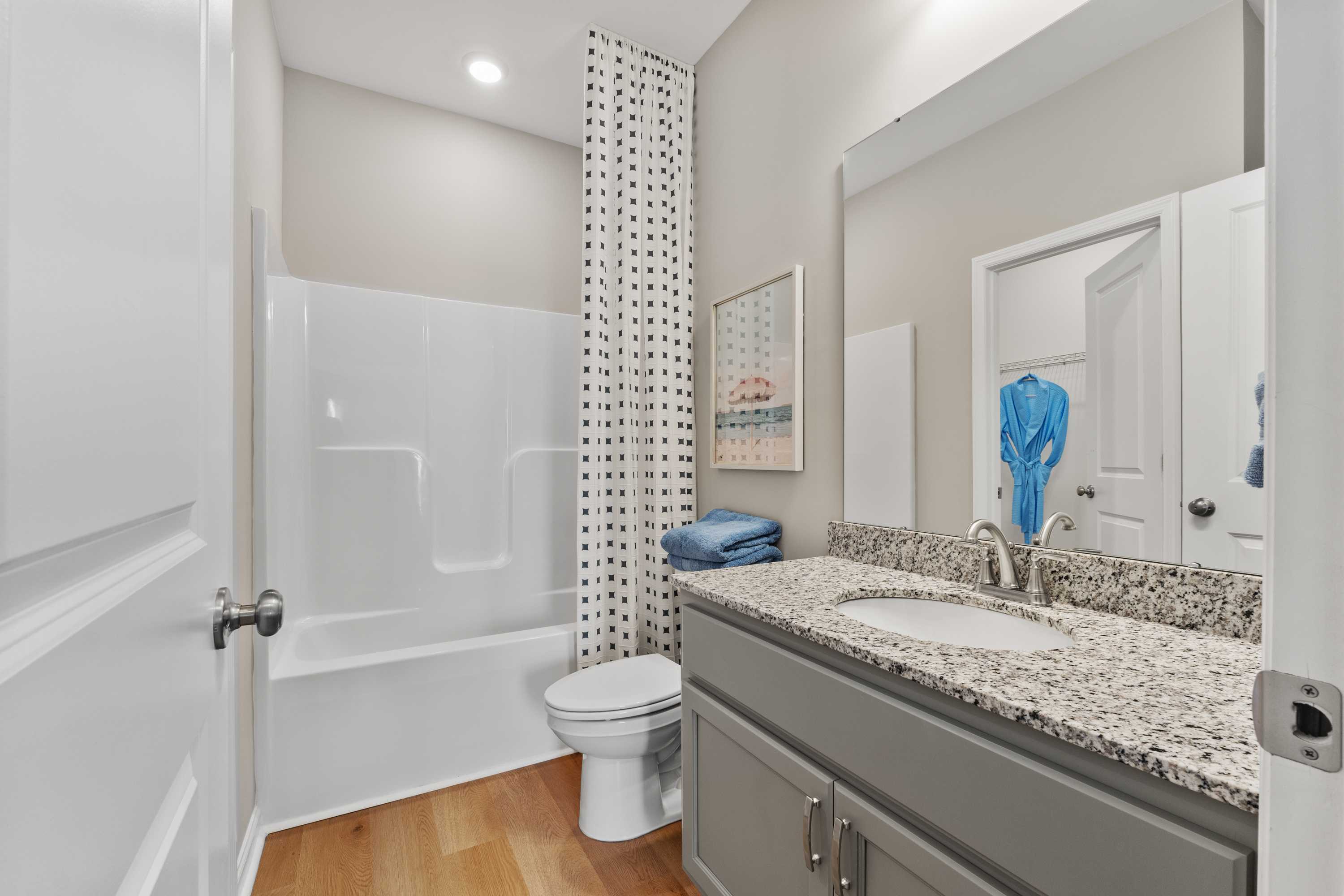 Guest bathroom at The Meadows at Hampton Cove in Owens Cross Roads AL with white tub-shower, gray vanity, granite countertop, blue towels