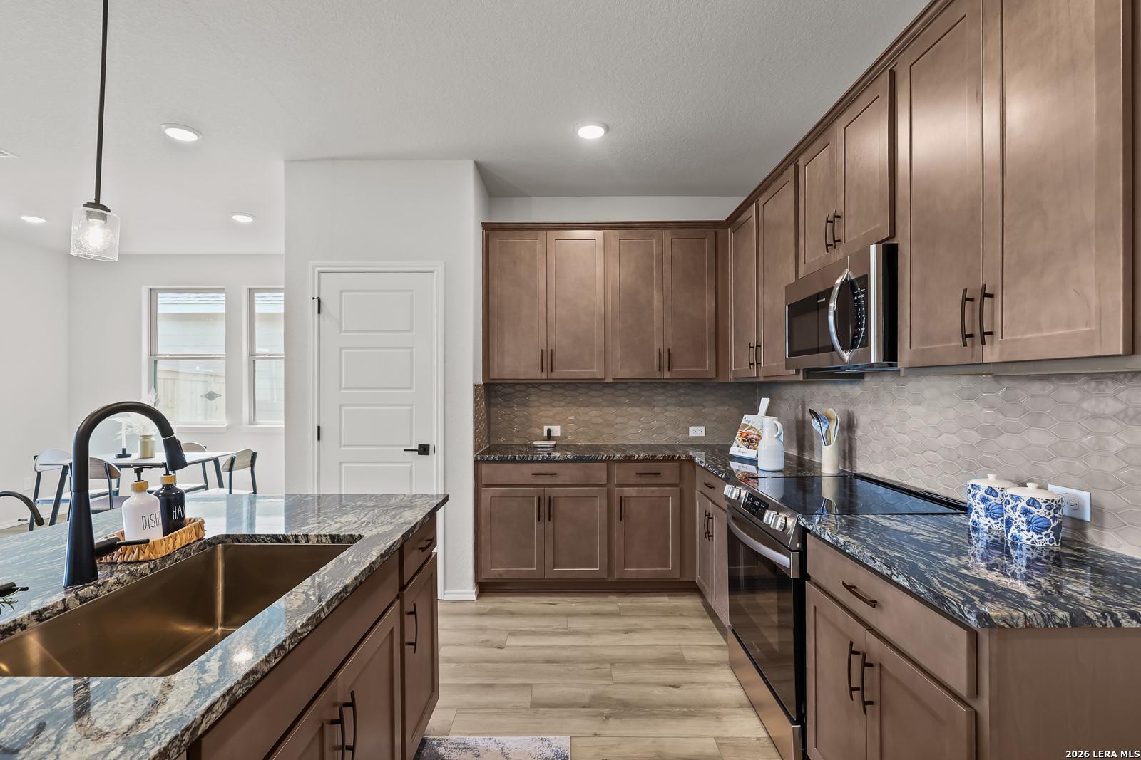 Modern open-concept kitchen with blue quartz island, stainless steel appliances, shaker cabinets in The Daphne H 3-bedroom home, Seguin, Texas