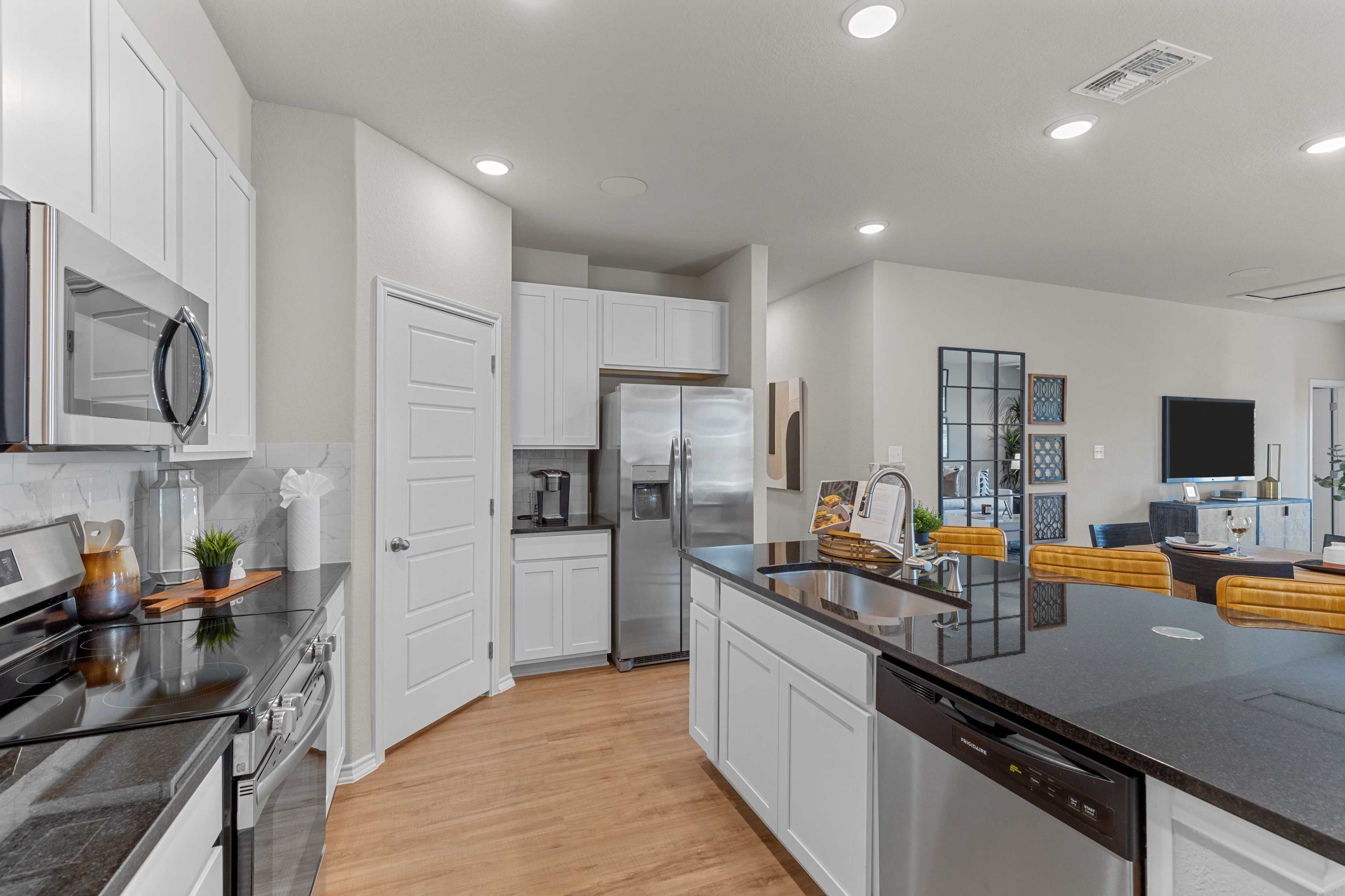 Spacious kitchen in The Sabine C by Davidson Homes, San Antonio TX: white cabinets, black granite island, stainless appliances