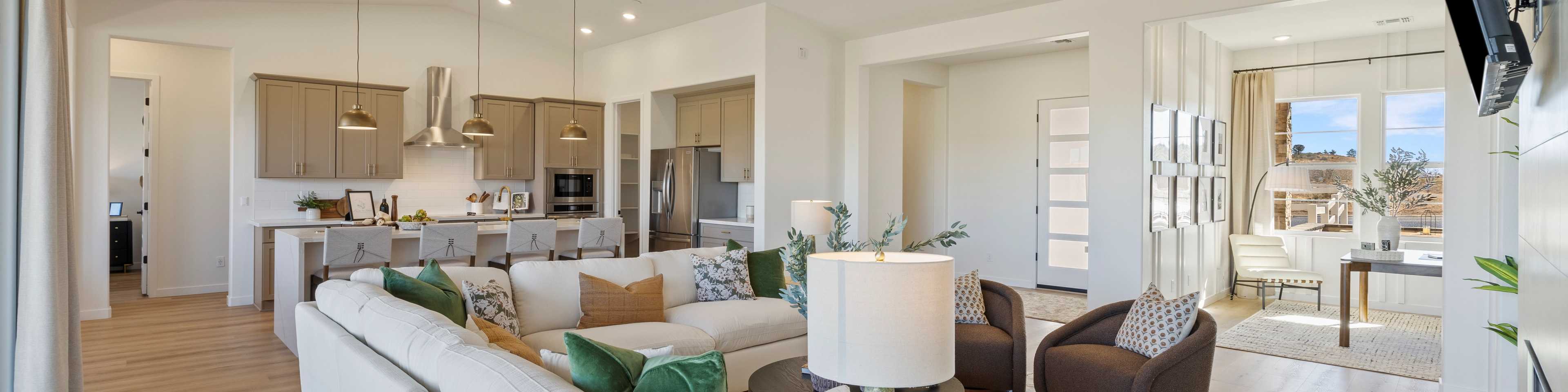 Spacious modern kitchen in Hidden Hills Prescott AZ by Davidson Homes with white cabinets, quartz island, bar stools, and hardwood floors