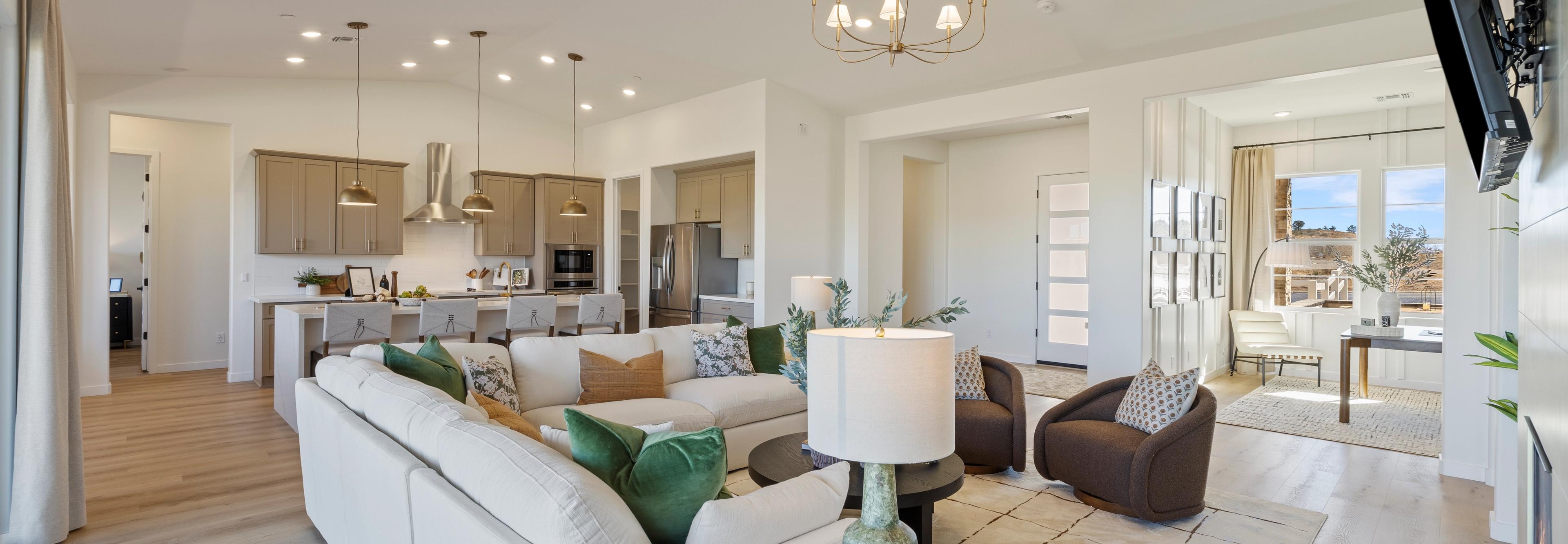 Spacious modern kitchen in Hidden Hills Prescott AZ by Davidson Homes with white cabinets, quartz island, bar stools, and hardwood floors