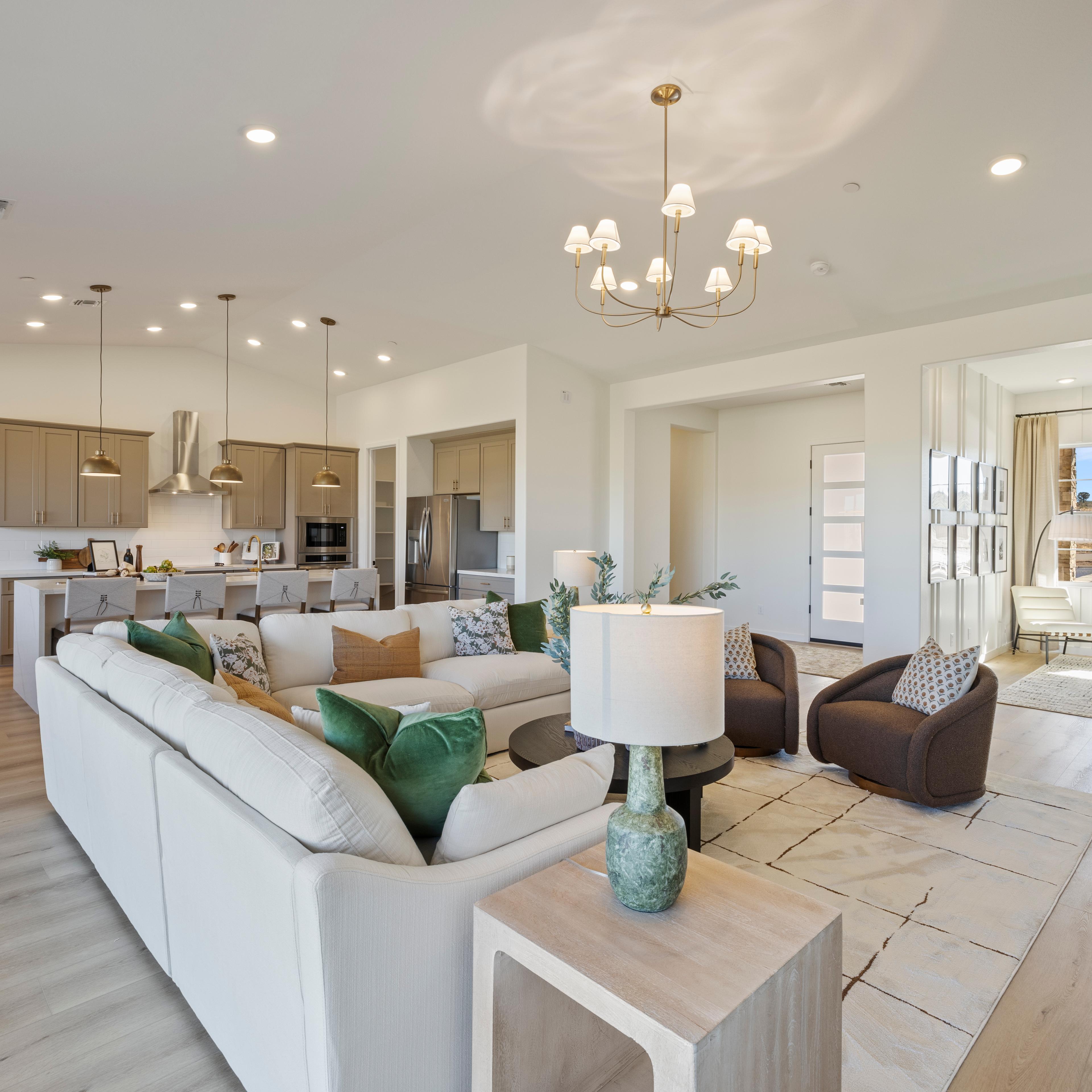 Spacious modern kitchen in Hidden Hills Prescott AZ by Davidson Homes with white cabinets, quartz island, bar stools, and hardwood floors