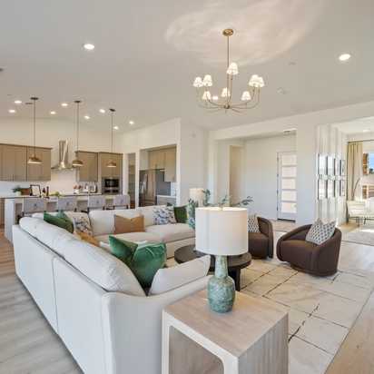 Spacious modern kitchen in Hidden Hills Prescott AZ by Davidson Homes with white cabinets, quartz island, bar stools, and hardwood floors
