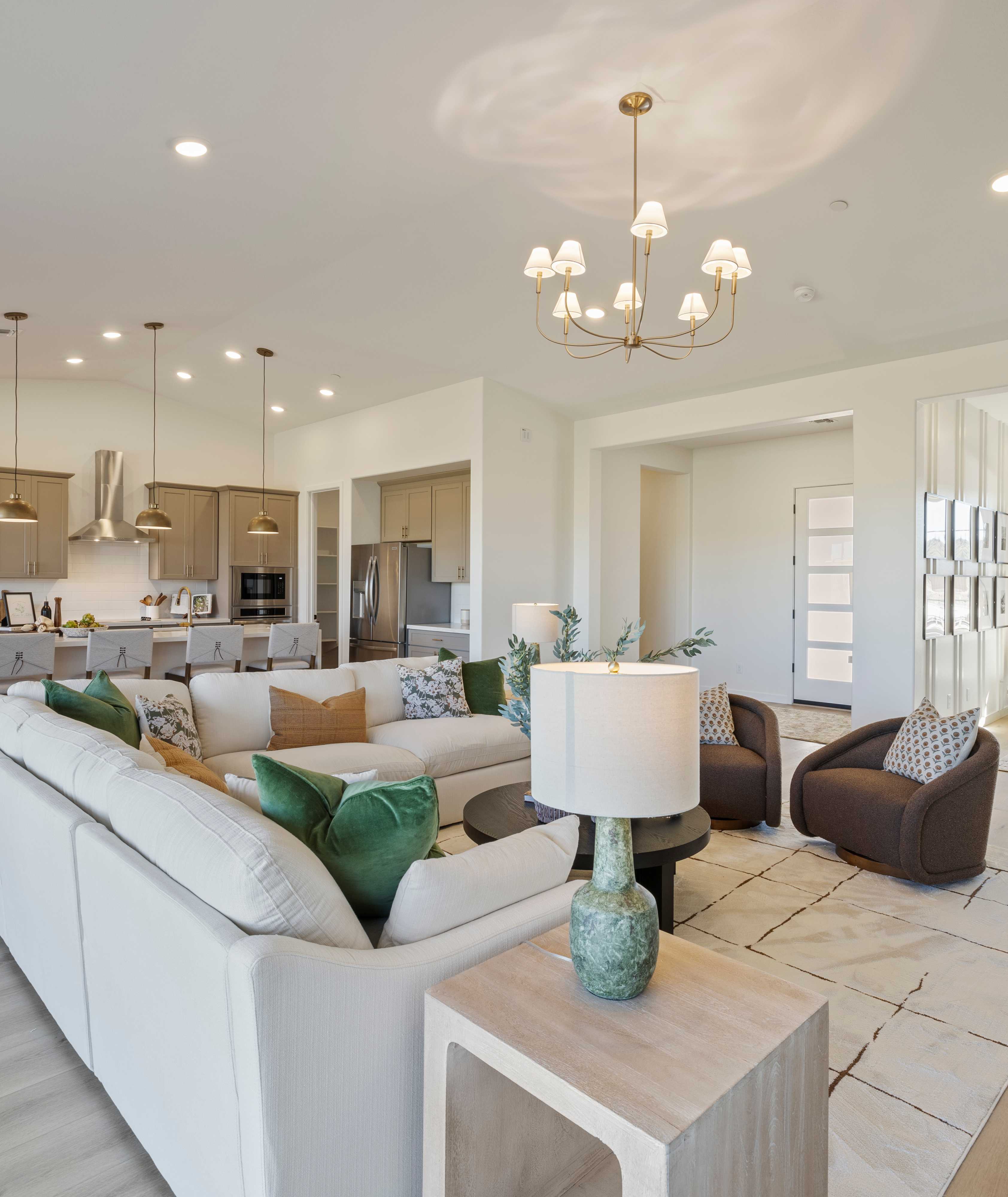 Spacious modern kitchen in Hidden Hills Prescott AZ by Davidson Homes with white cabinets, quartz island, bar stools, and hardwood floors