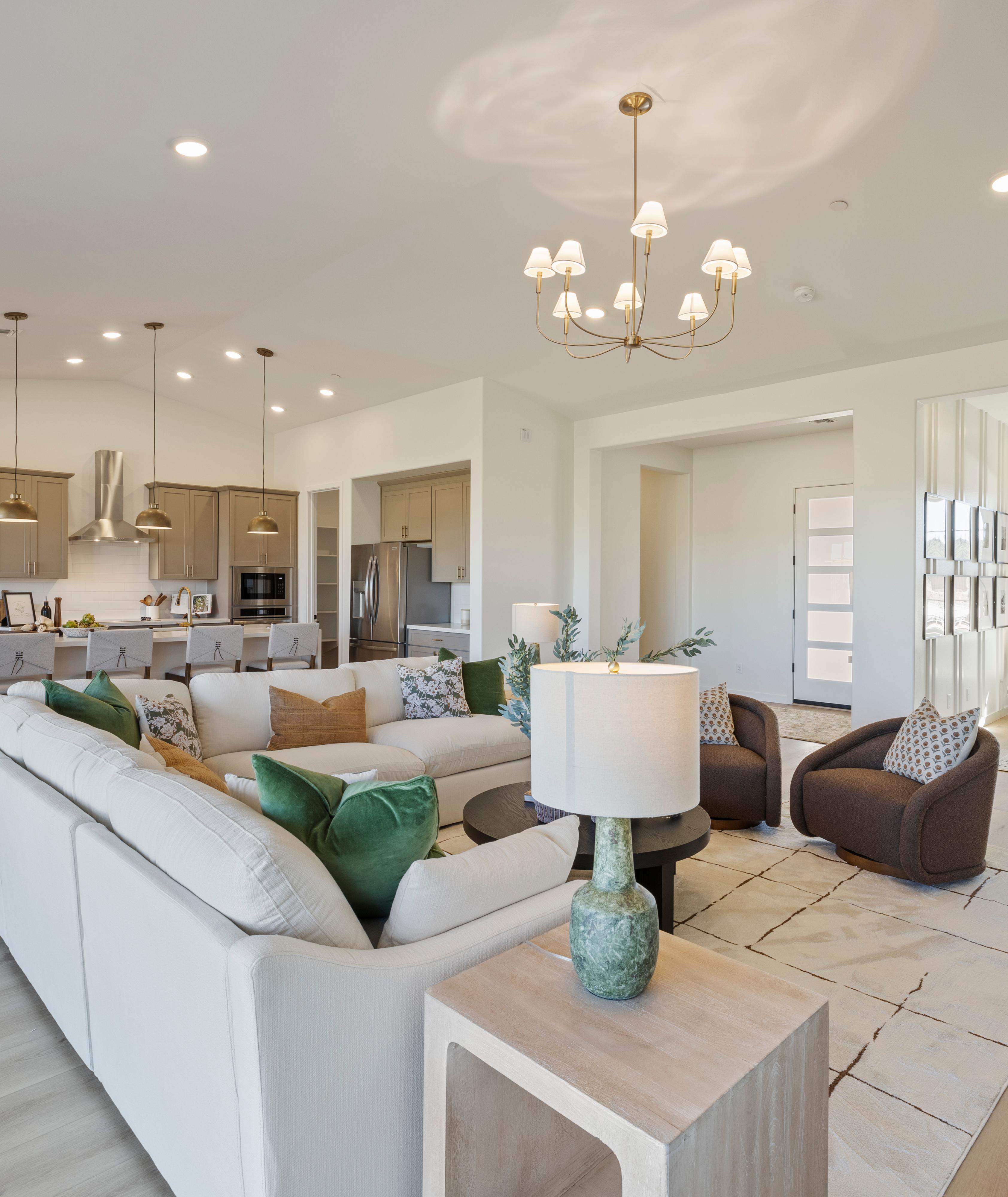 Spacious modern kitchen in Hidden Hills Prescott AZ by Davidson Homes with white cabinets, quartz island, bar stools, and hardwood floors