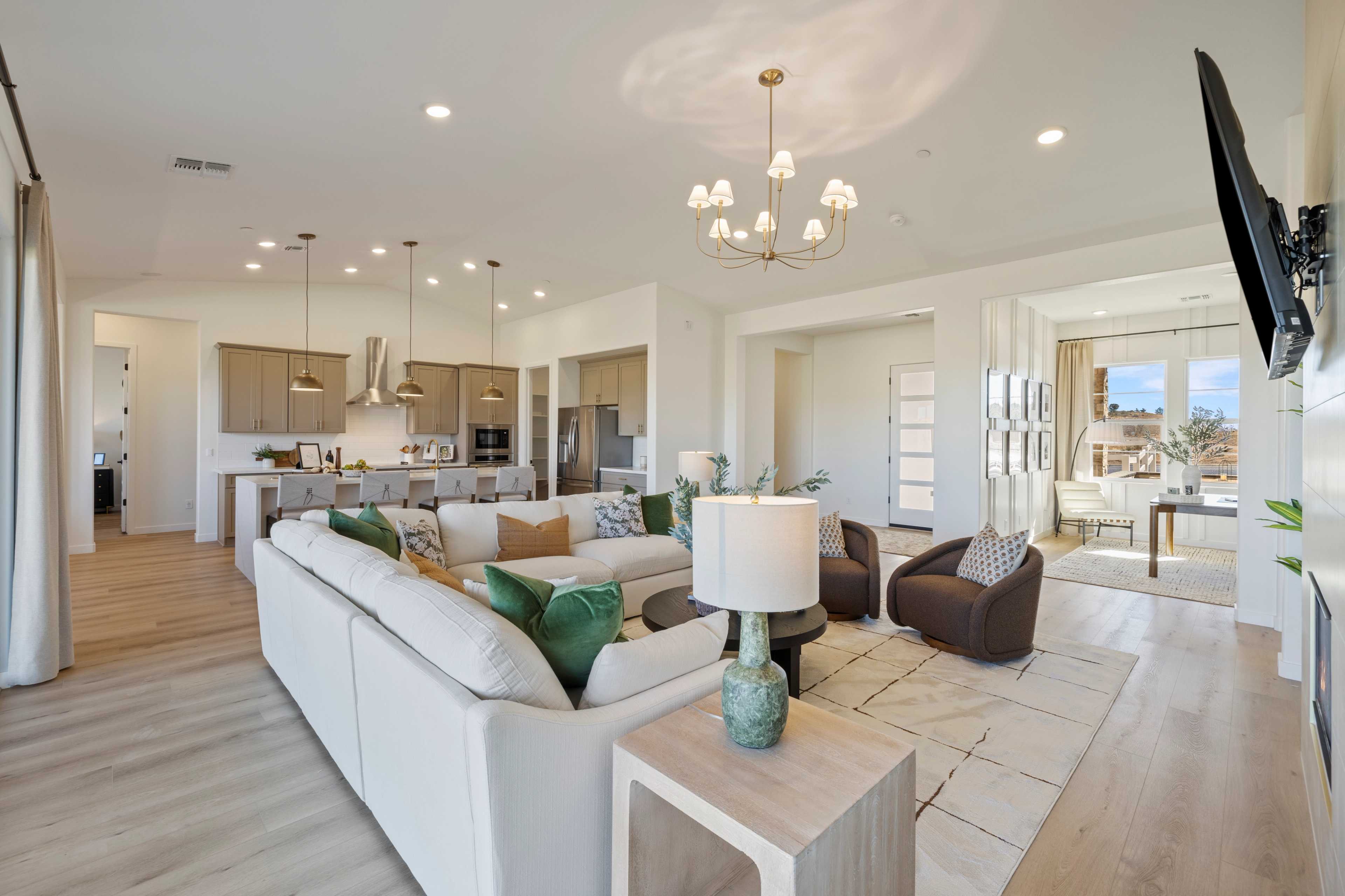 Spacious open-concept living room and kitchen in Hidden Hills Prescott AZ by Davidson Homes with hardwood floors, modern chandelier, and desert views