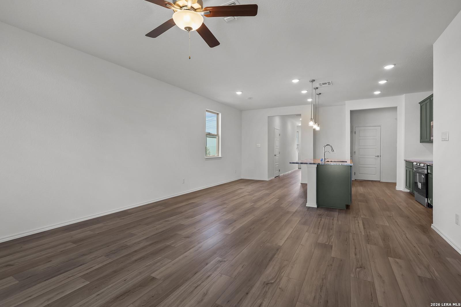 Open-concept living area with wood-look flooring and kitchen island in The Brazos B home in Agave, San Antonio, Texas.