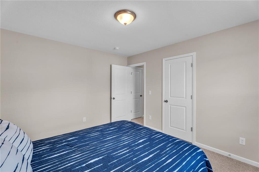 Cozy secondary bedroom featuring beige walls, blue striped bedding, and white doors in Davidson Homes The Bartlett, Phenix City, Alabama