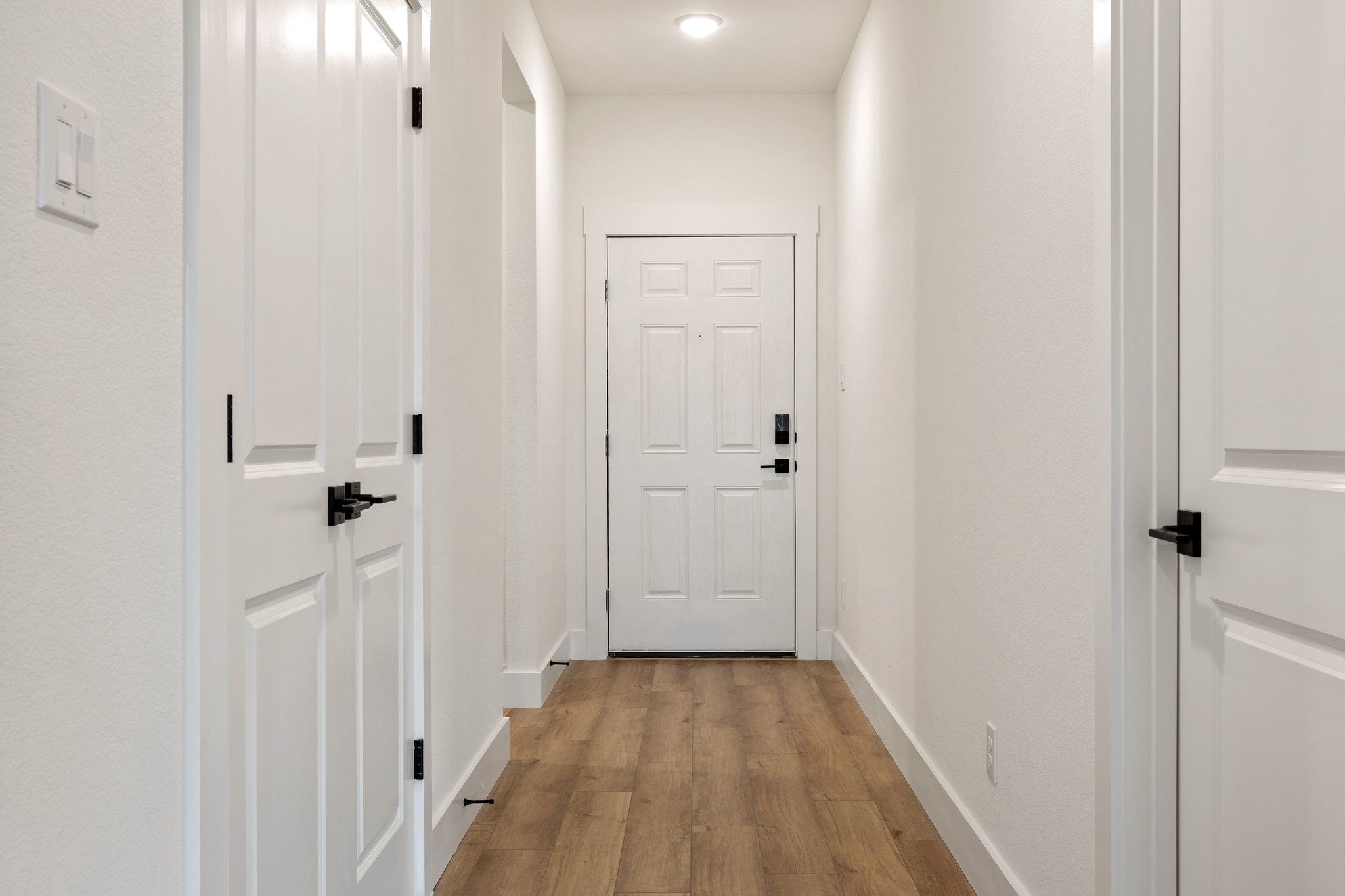 Bright entryway hallway with modern white doors and wood-look floors in The Rockford C floor plan at Waverly Estates.