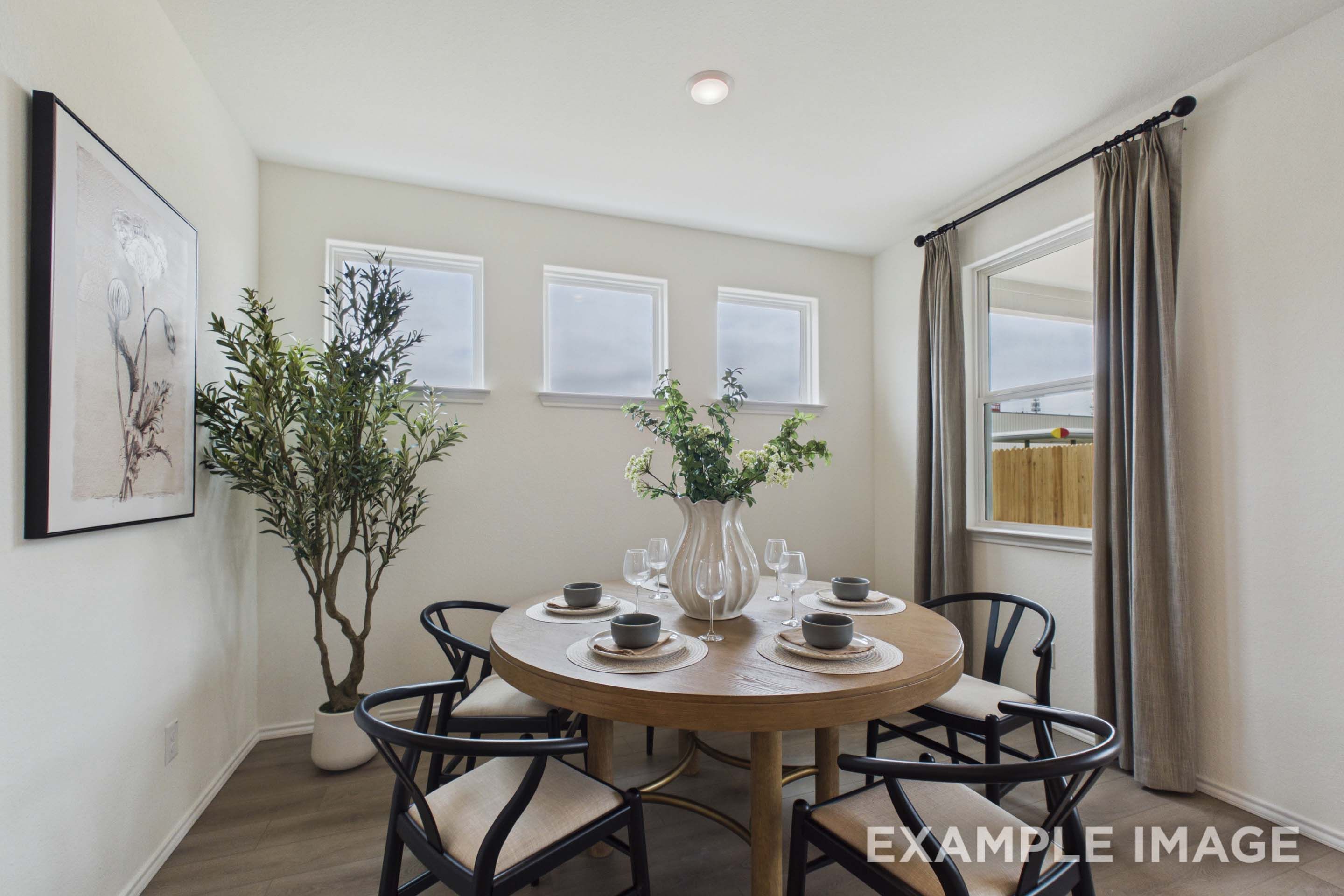 Bright dining room in The Laurel G floor plan featuring a round wooden table, modern chairs, and natural light.