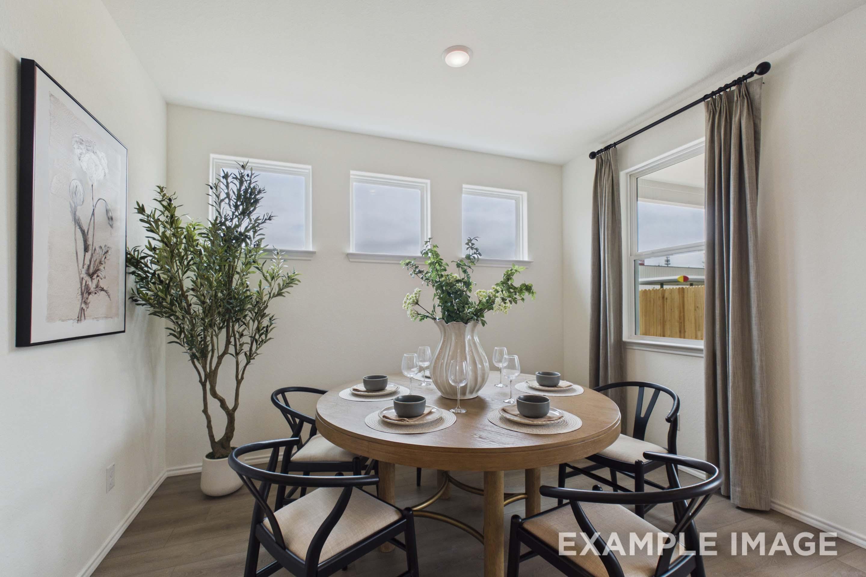 Bright dining room in The Laurel G floor plan featuring a round wooden table, modern chairs, and natural light.