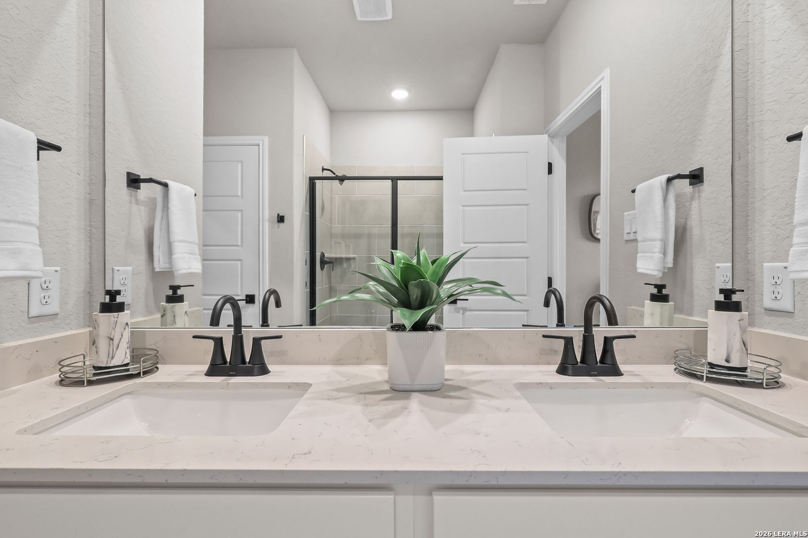 Modern master bathroom with dual vanities and quartz countertops in The Daphne H floor plan at Hannah Heights, Seguin.