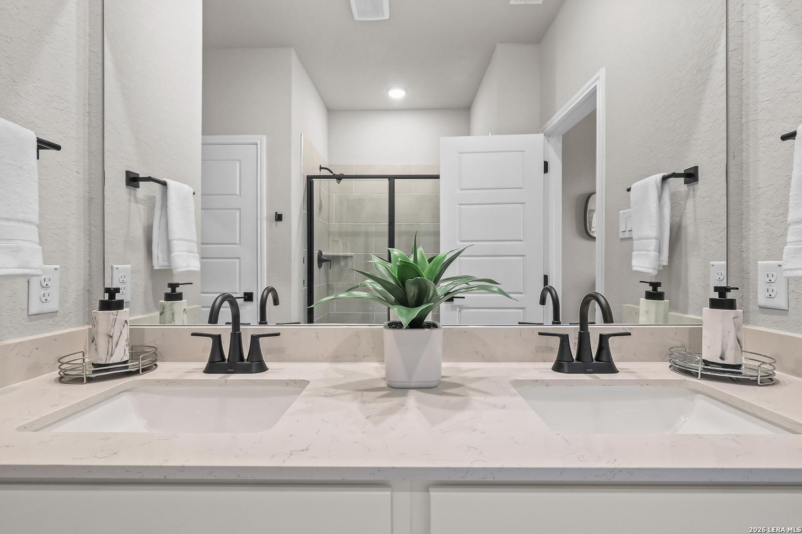 Modern master bathroom with dual vanities and quartz countertops in The Daphne H floor plan at Hannah Heights, Seguin.