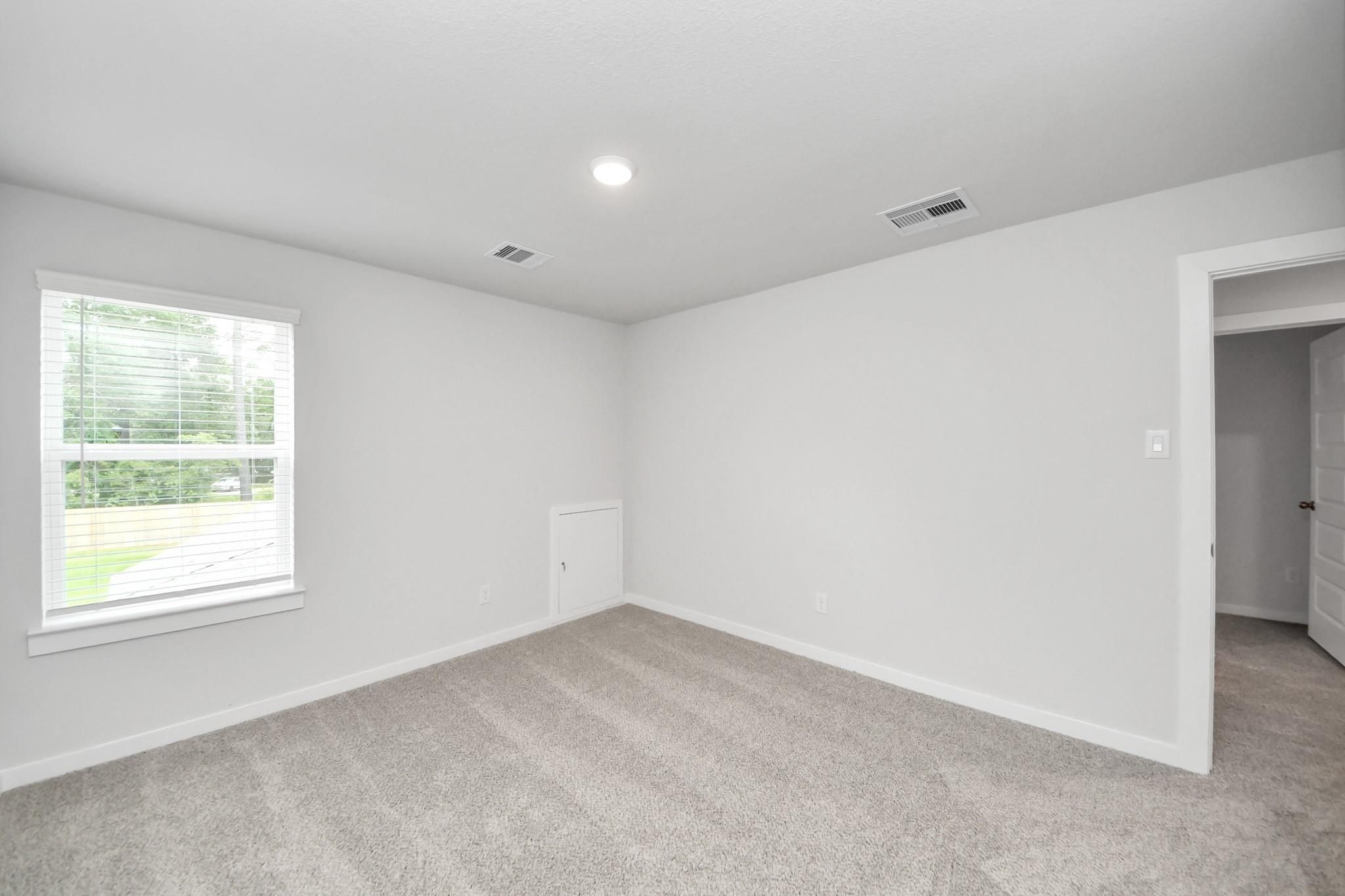 Spacious secondary bedroom with neutral carpet in The Sabine E floor plan at Liberty Estates, Cleveland, Texas.