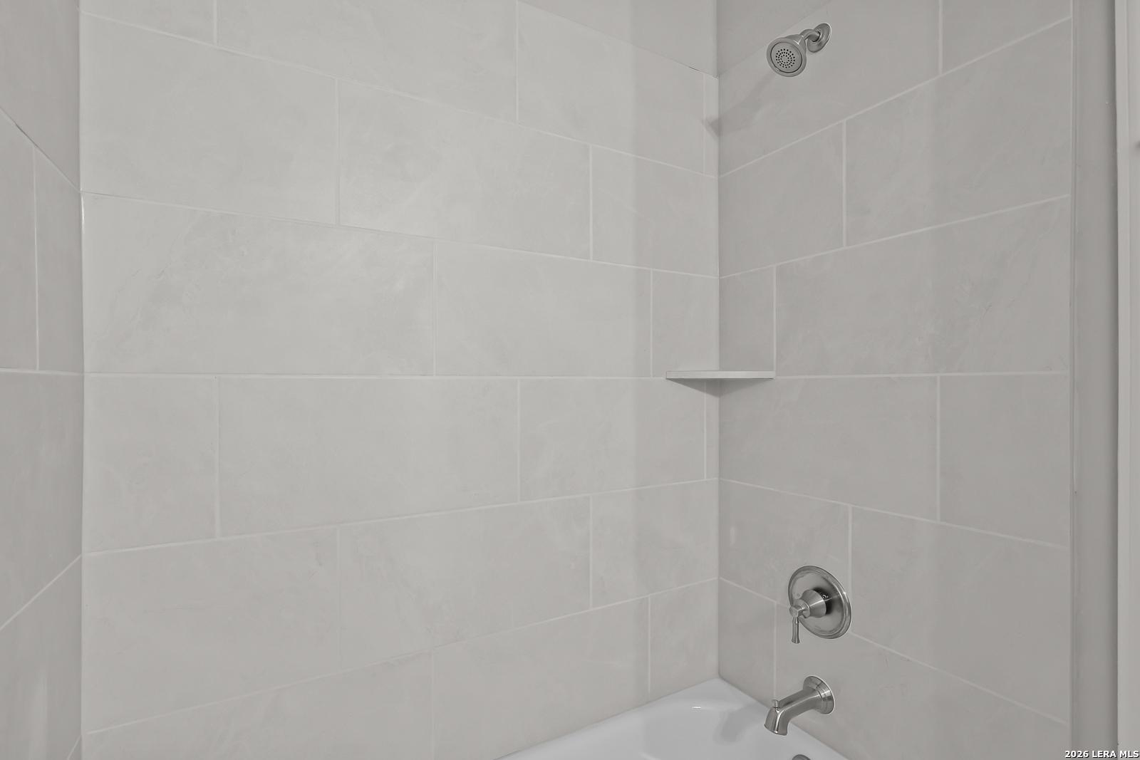 Modern white subway tile shower enclosure and soaking tub in master bath of Davidson Homes The Rockford G, Ladera, San Antonio