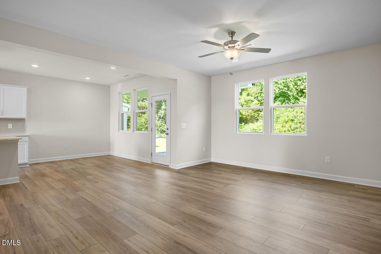 Bright open-concept living area with wood-look flooring and ceiling fan in Davidson Homes The Willow C, Zebulon, NC