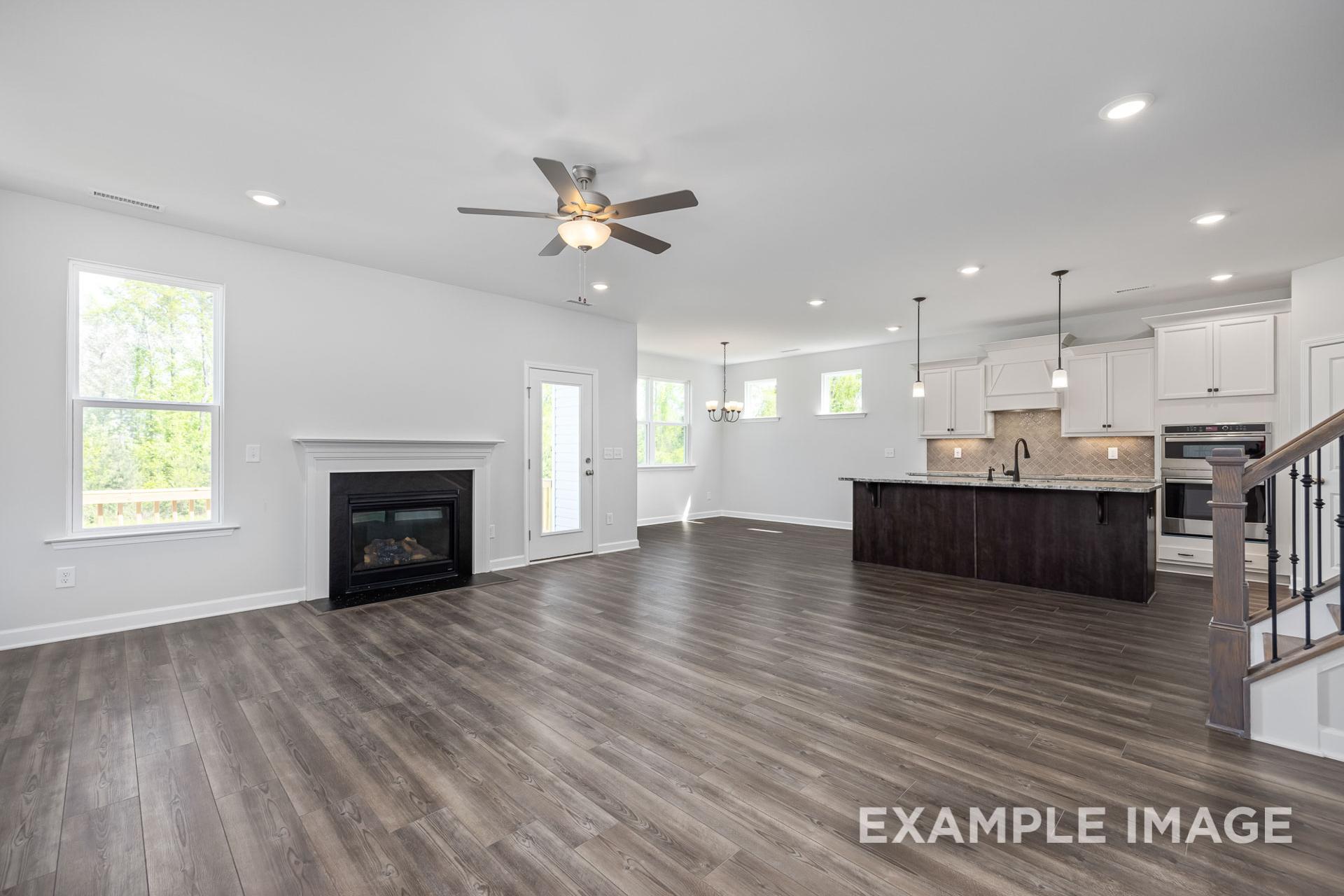 Spacious open-concept living room in The Grace C with gas fireplace, modern kitchen island, hardwood floors