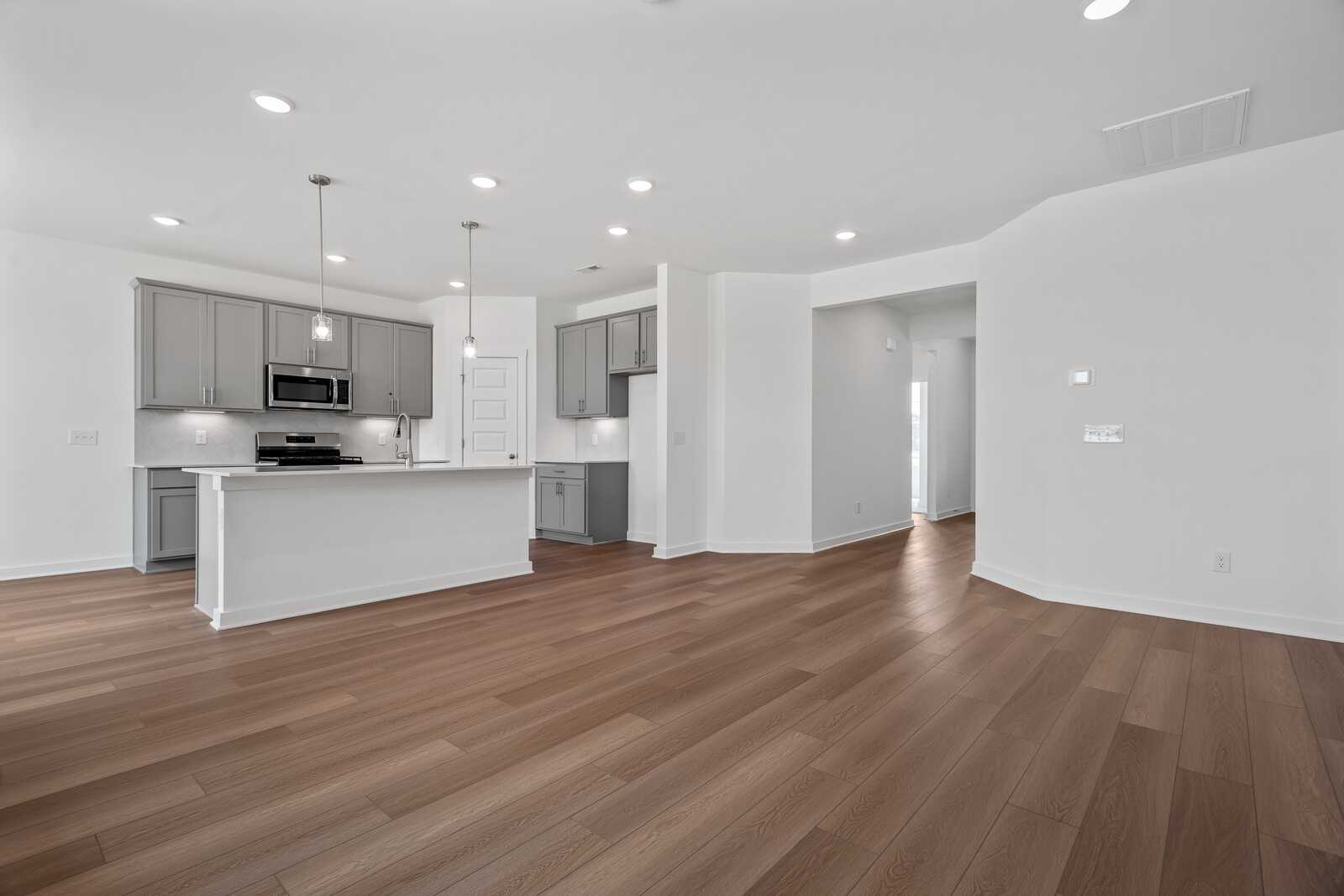 Spacious open-concept kitchen in The Asheville with white island, gray cabinets, hardwood floors, and recessed lighting