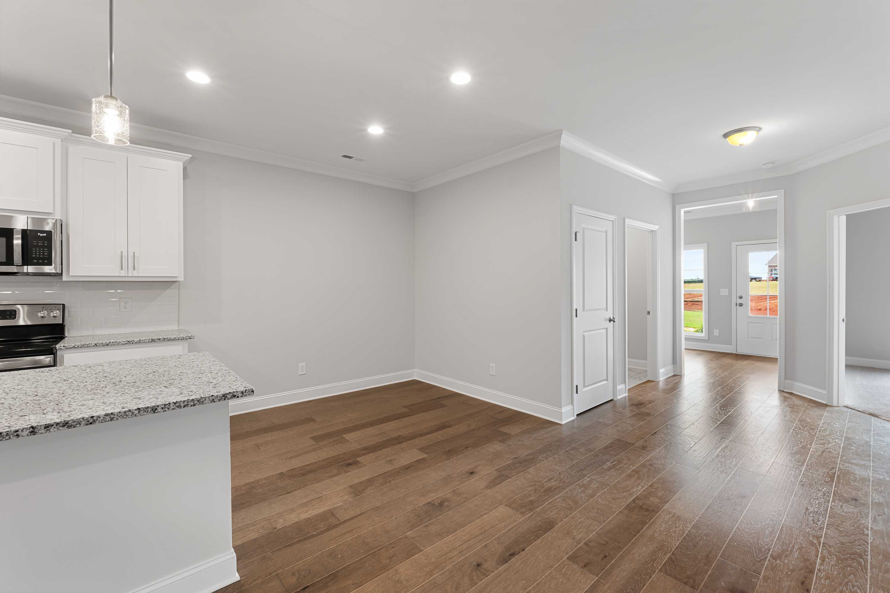 Spacious open-concept kitchen in The Copeland B with white cabinets, granite island, stainless appliances, hardwood floors, Madison AL home