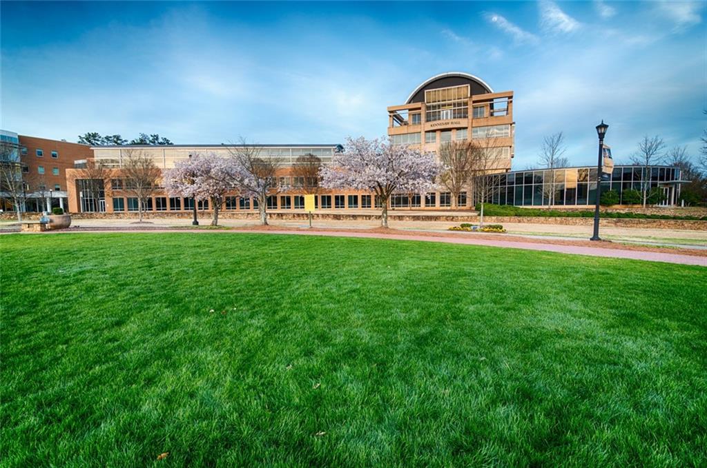 Modern brick and glass building with curved roof amid blooming cherry trees and green lawn in The Village at Shallowford, Kennesaw, Georgia