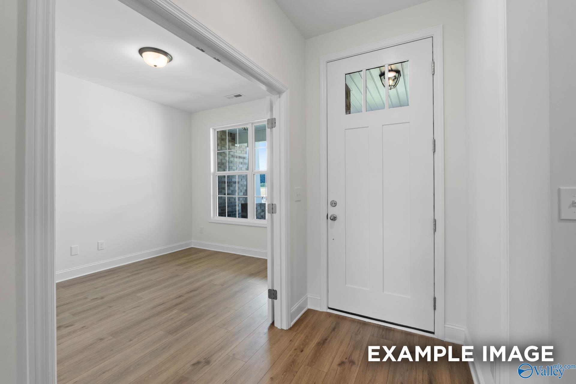 Bright entryway with white glass-paneled door, oak floors, and windowed room in Davidson Homes The Rockford B, Athens, AL