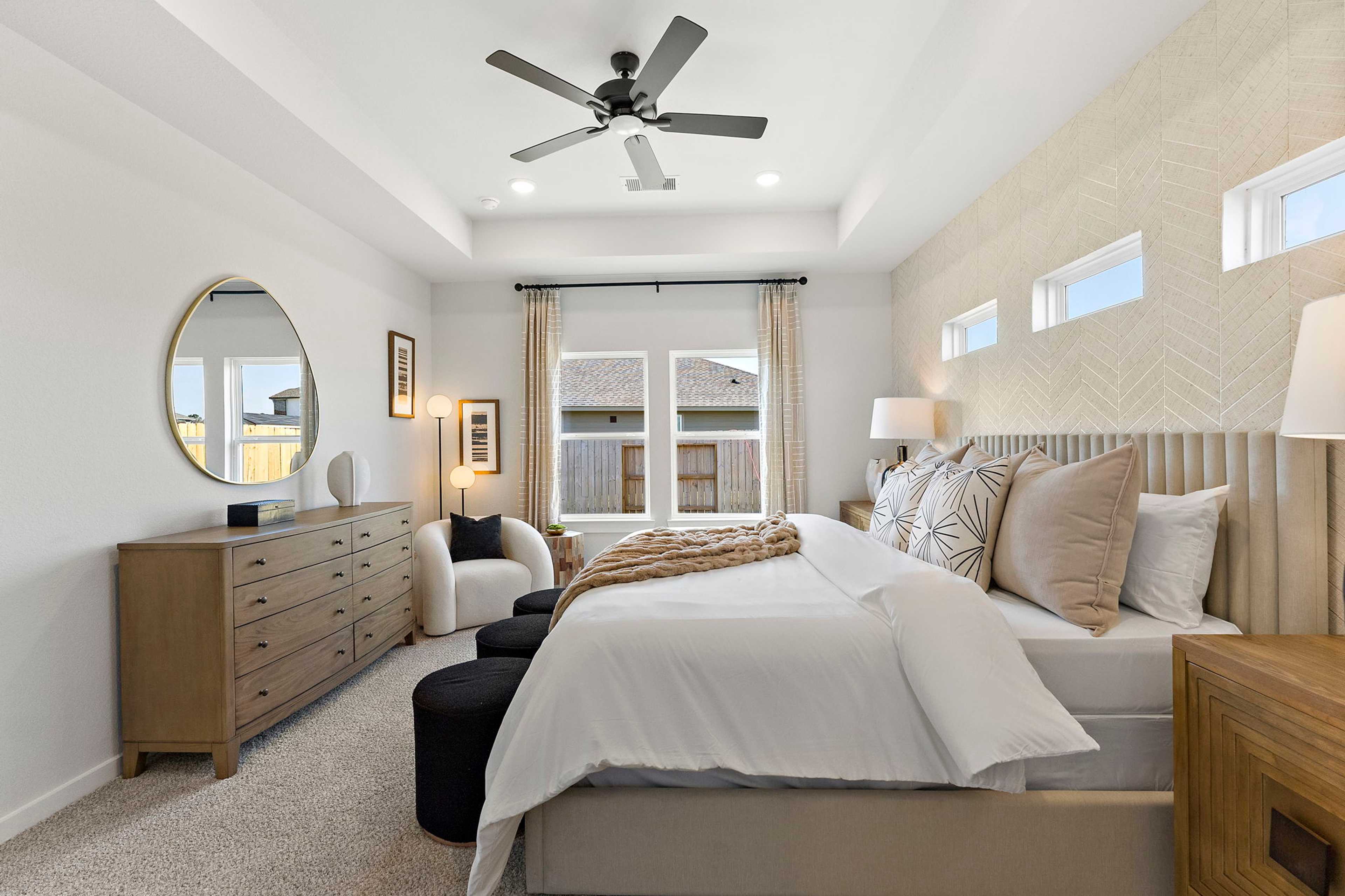 Spacious master bedroom at Sundance Cove in Crosby Texas with ceiling fan, upholstered bed, large windows, and textured walls