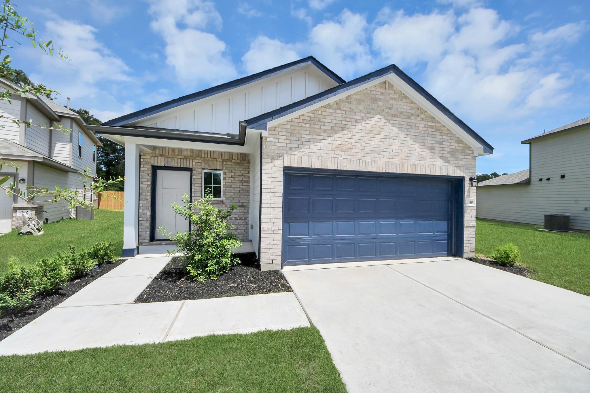 Brick exterior with blue garage door and covered porch at Davidson Homes' The Sabine F in Liberty Estates, Cleveland, Texas