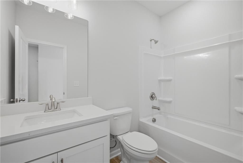 Bright white bathroom with vanity, mirror, toilet, and tub shower combo in Davidson Homes Oconee B plan, Canton, Georgia