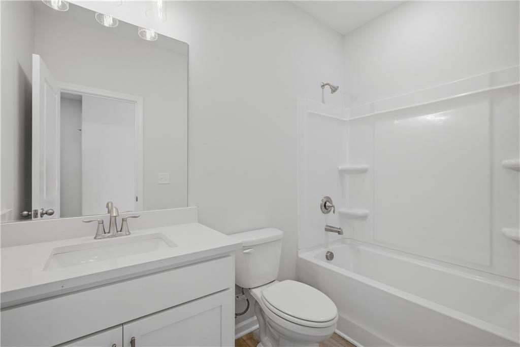 Bright white bathroom with vanity, mirror, toilet, and tub shower combo in Davidson Homes Oconee B plan, Canton, Georgia