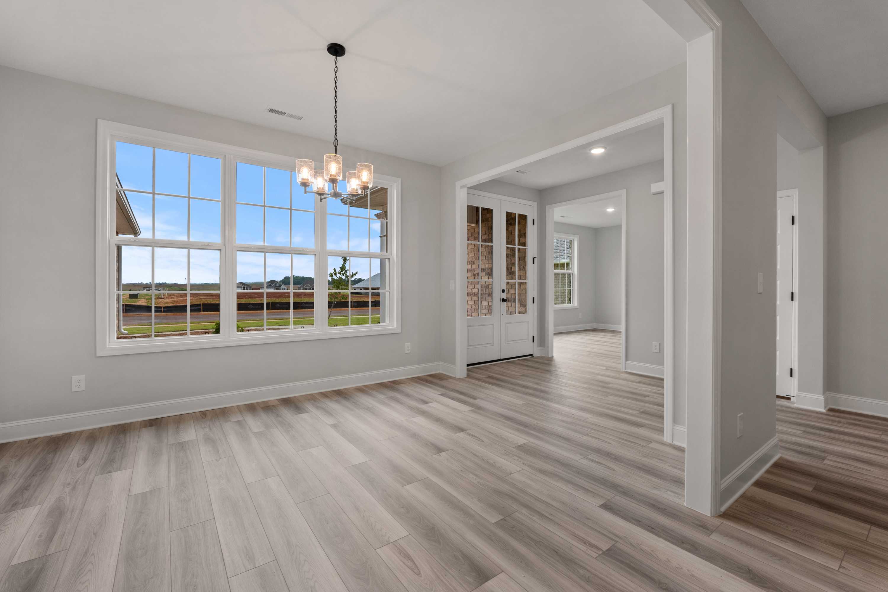 Bright dining area in The Oxford home featuring large windows with field views, chandelier, French doors, and open layout
