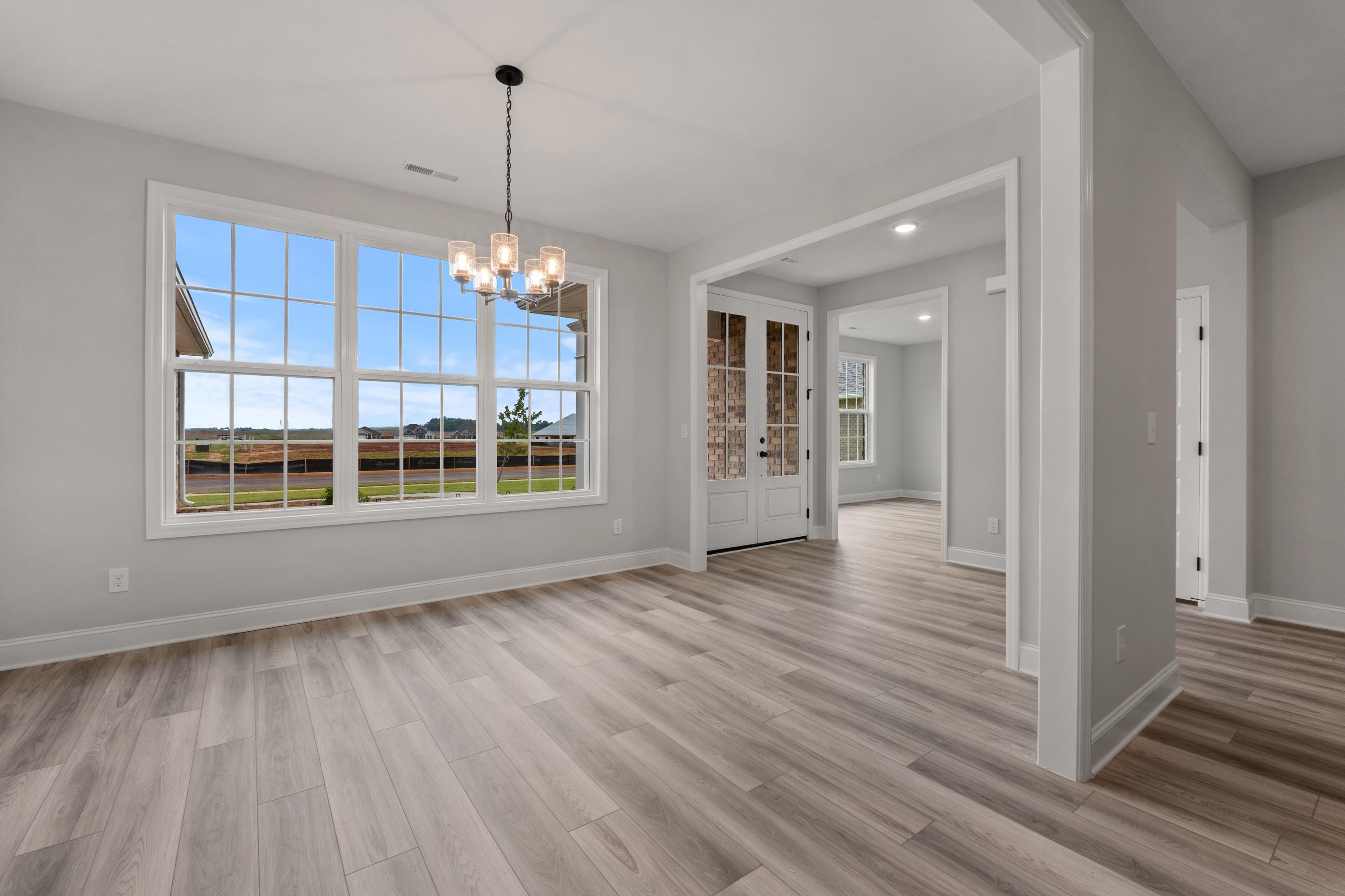 Bright dining area in The Oxford home featuring large windows with field views, chandelier, French doors, and open layout