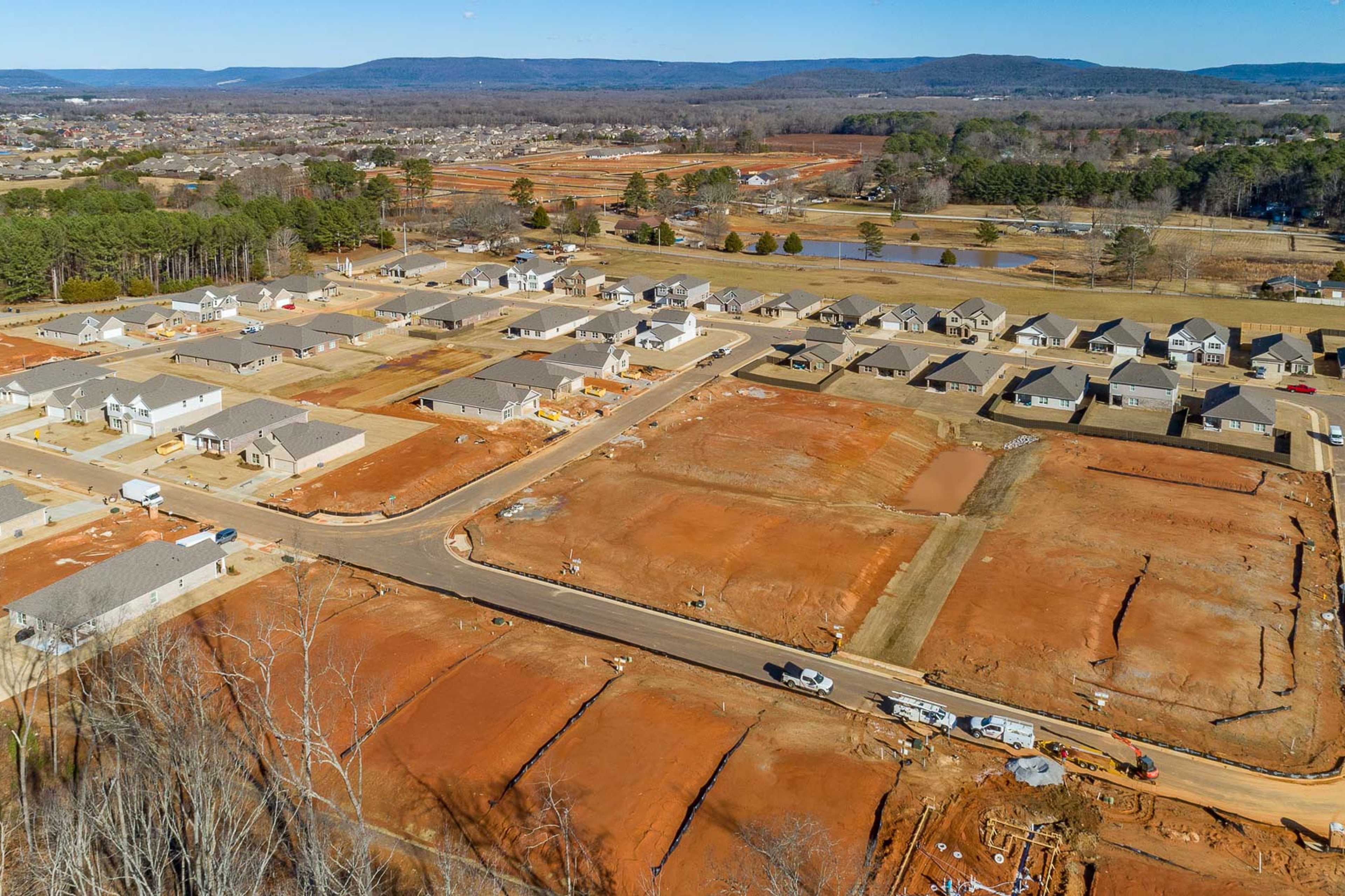 Aerial view of Monteagle Cove neighborhood construction in Owens Cross Roads Alabama with new homes red clay lots and wooded hills