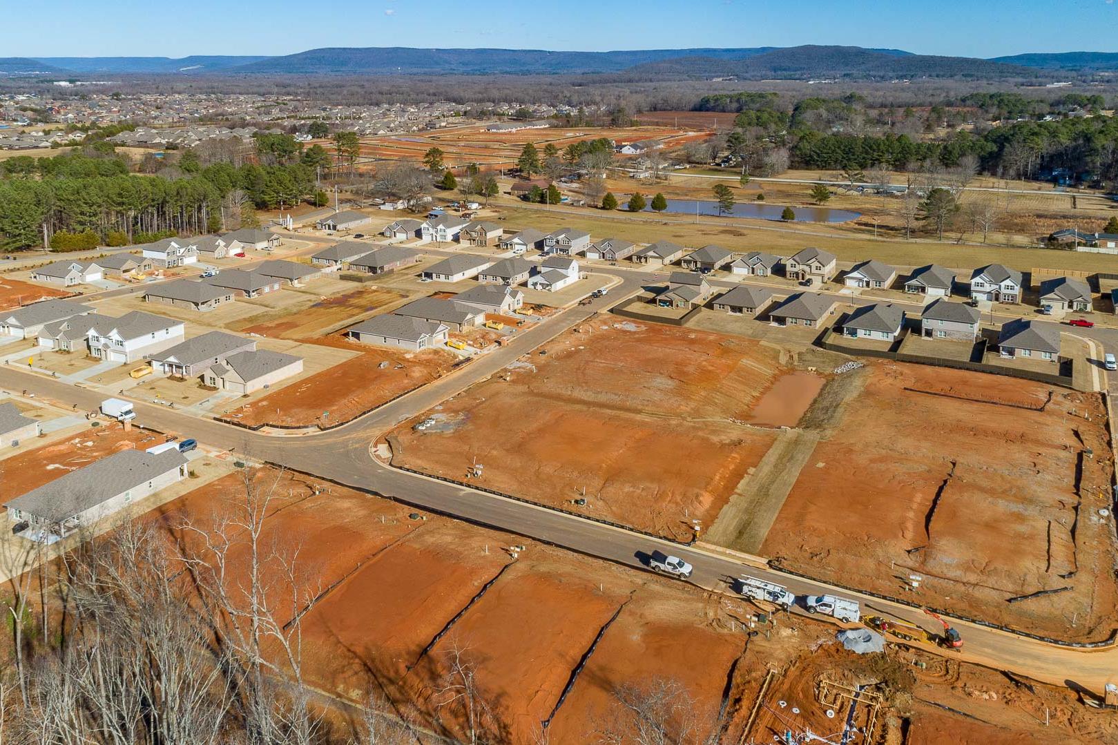 Aerial view of Monteagle Cove neighborhood construction in Owens Cross Roads Alabama with new homes red clay lots and wooded hills