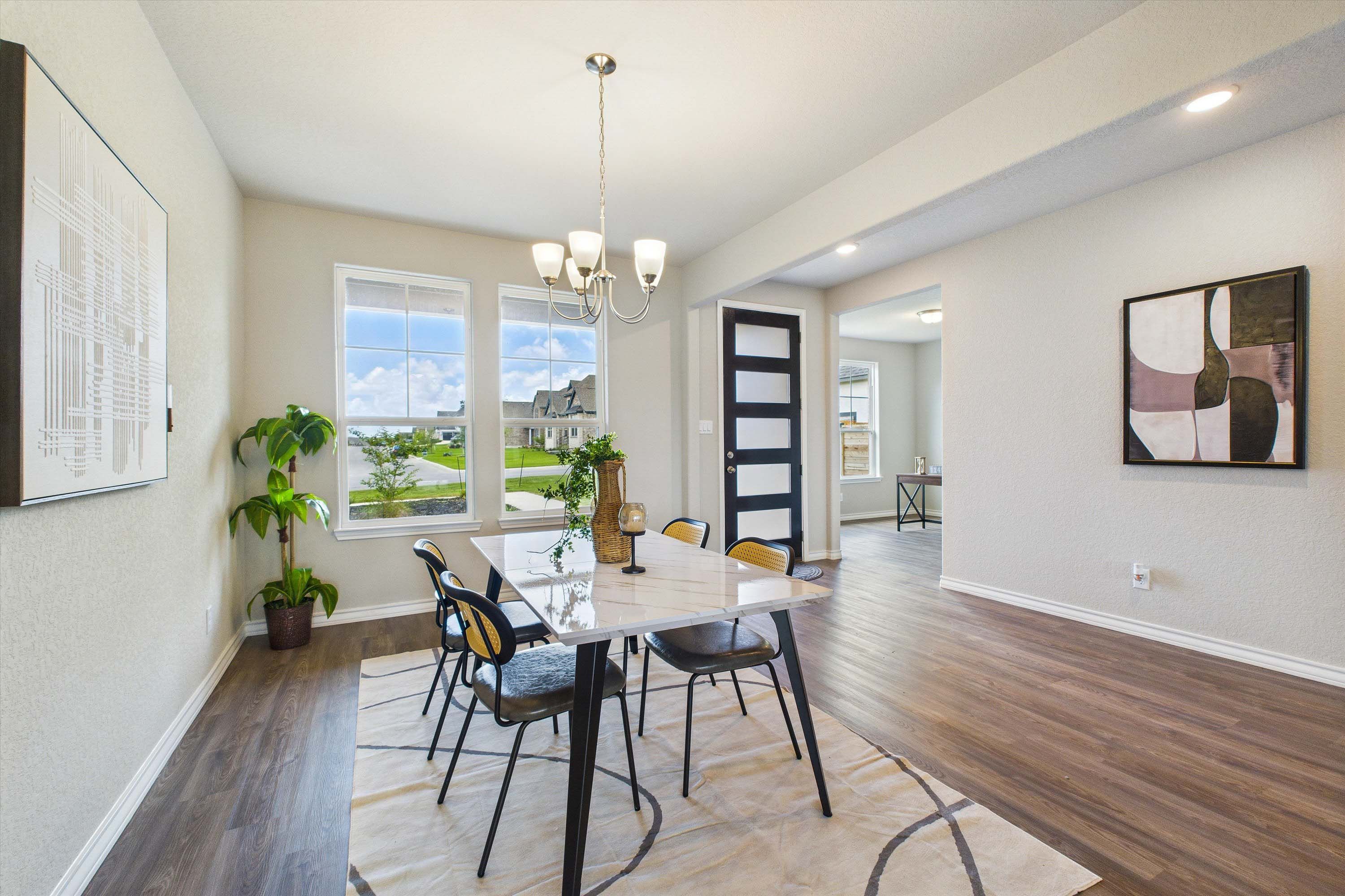 Modern dining area in The Foster E home design featuring elegant marble-top table, chic chairs, and open-concept layout.