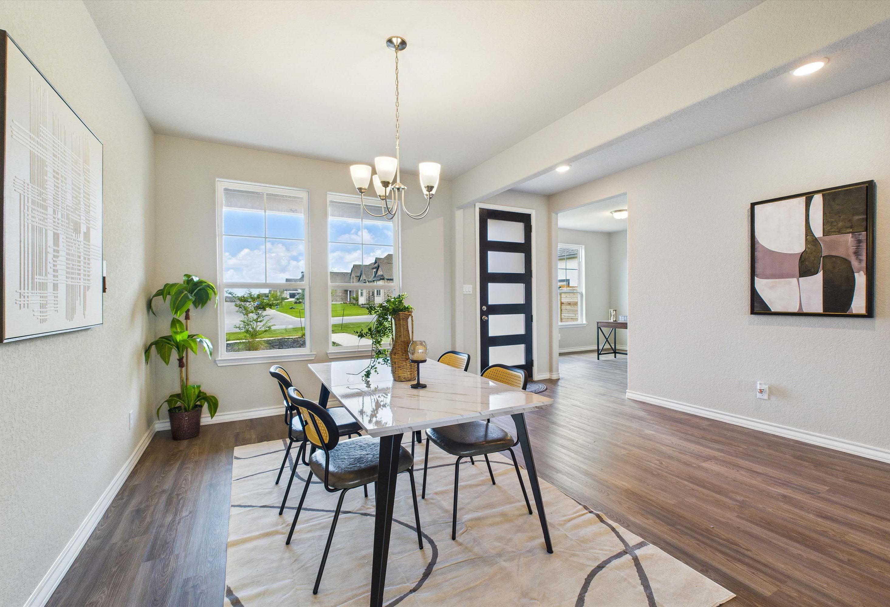 Modern dining area in The Foster E home design featuring elegant marble-top table, chic chairs, and open-concept layout.