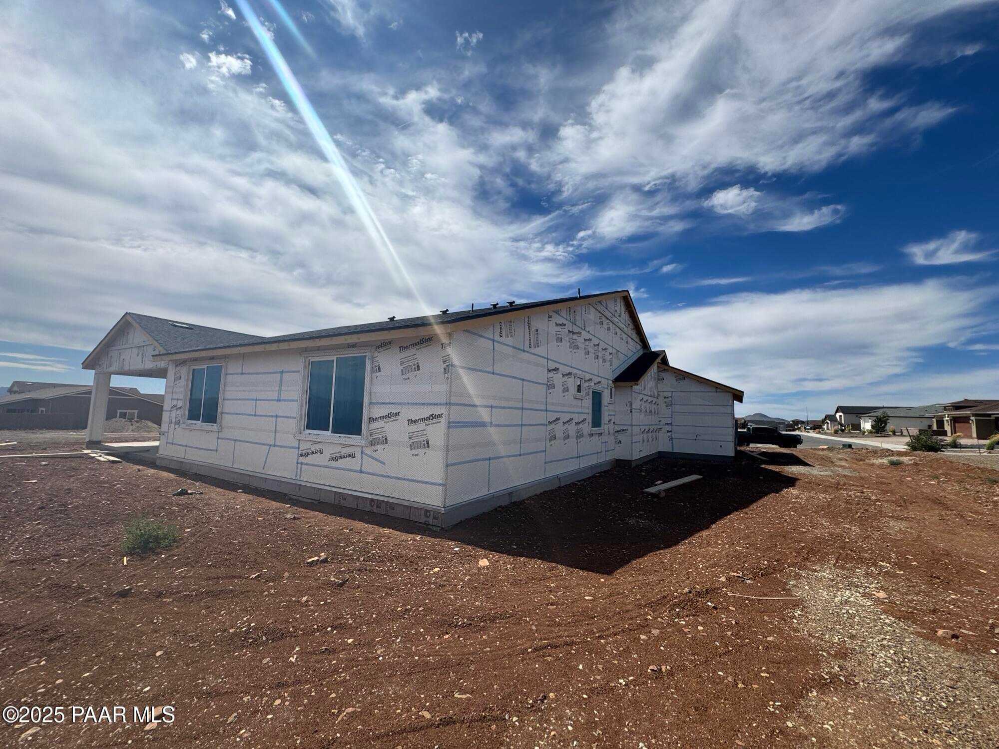 Under-construction single-story home with white sheathing, blue windows, and 4-car garage in Morningstar, Prescott Valley, Arizona - Evermore Homes The Sunrise A