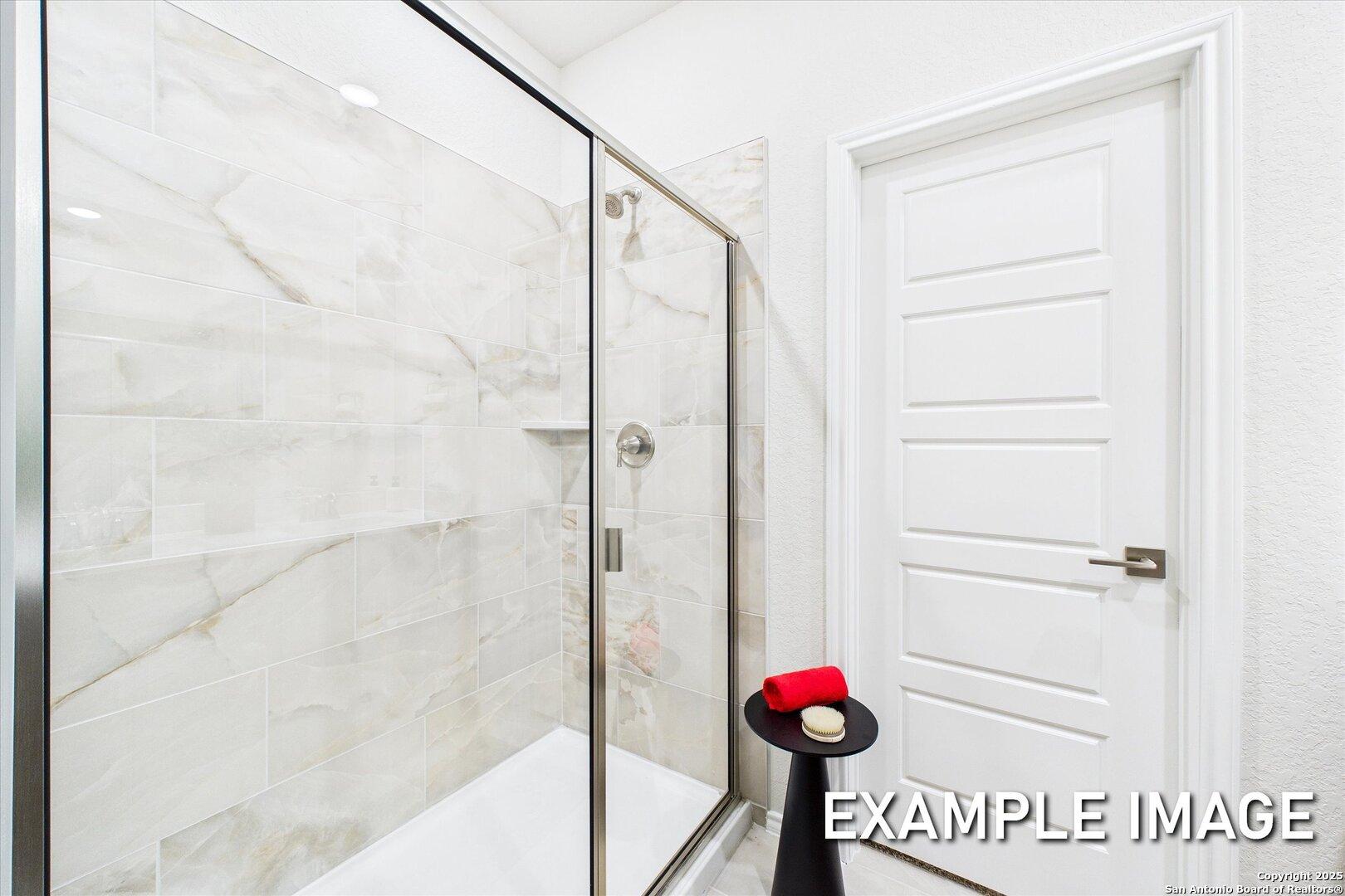 Elegant master bathroom featuring frameless glass shower, white subway tile, and rainfall showerhead in Davidson Homes The Brazos C, Agave San Antonio