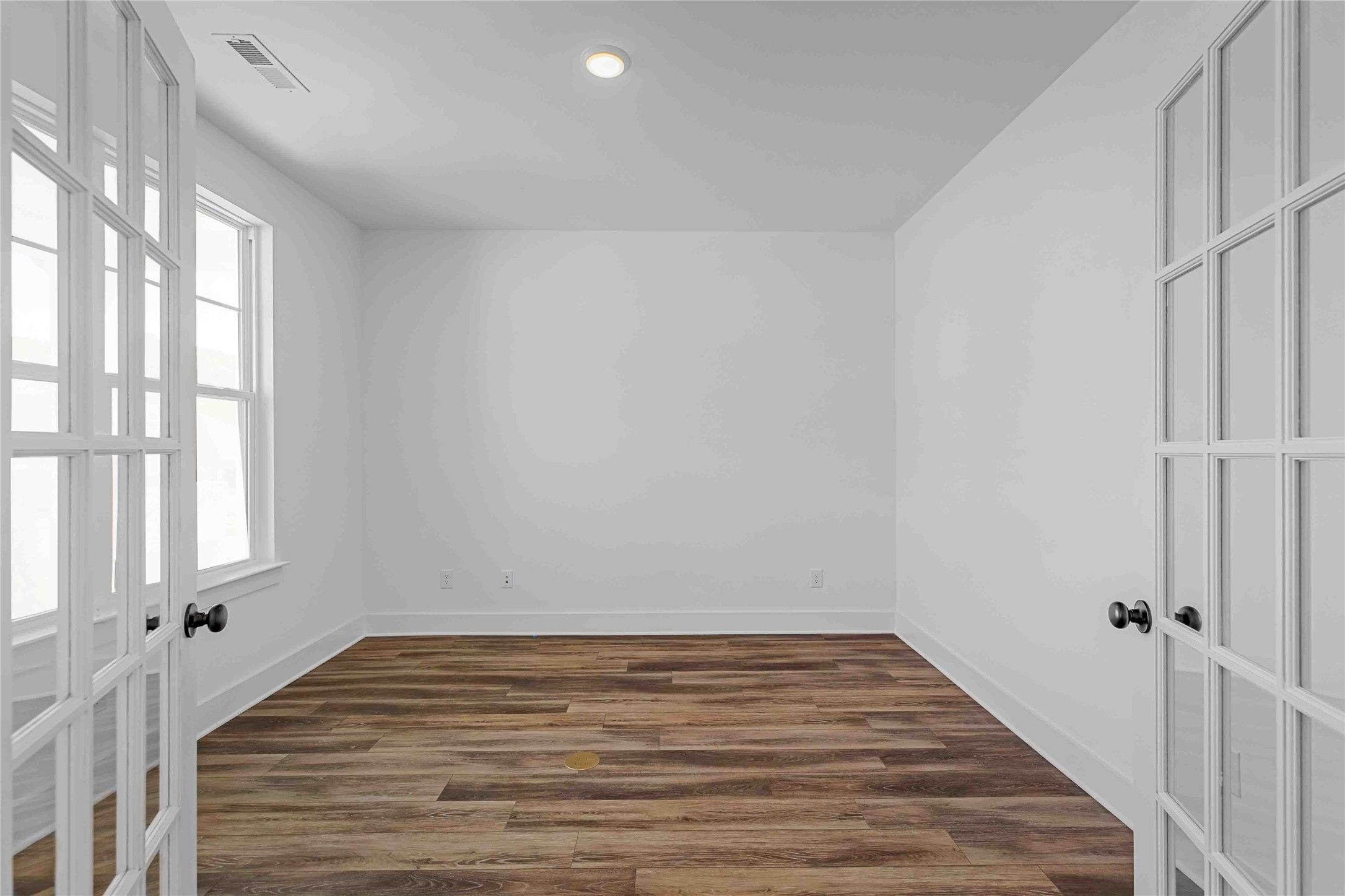 Bright home office with French doors and wood-look flooring in The Ash O floor plan by Davidson Homes in Heartland, TX.
