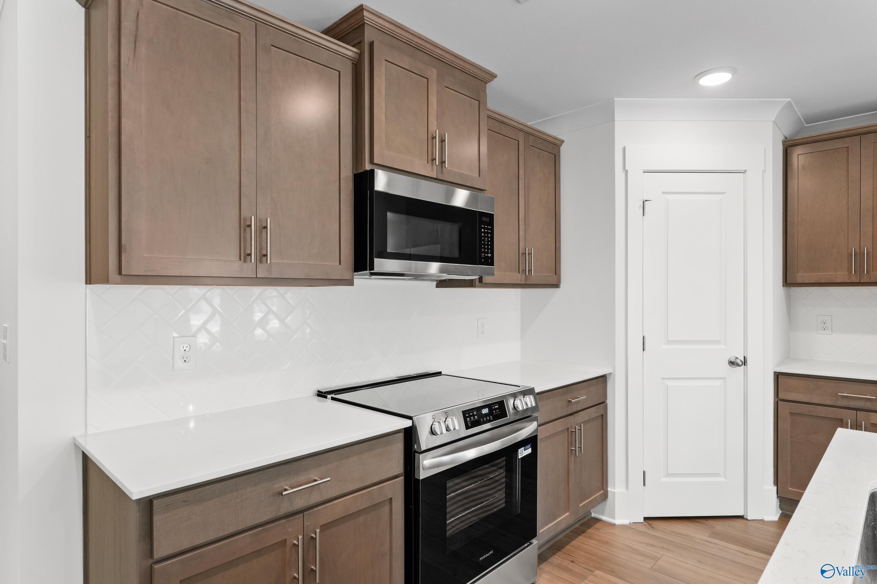 Modern kitchen with oak shaker cabinets, stainless steel microwave and oven, white quartz counters in The Daphne C home, Arab, Alabama