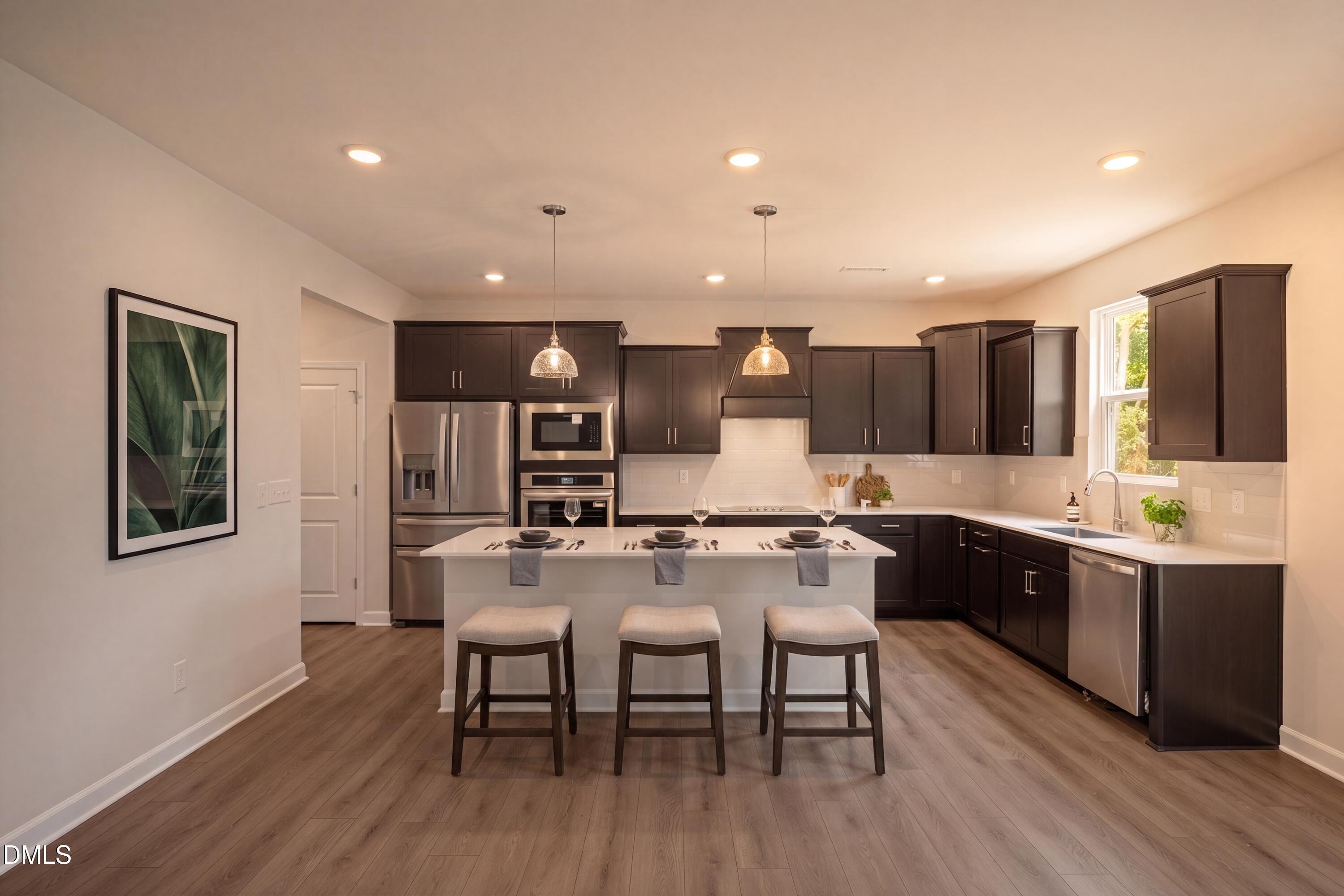 Modern kitchen with dark cabinets, white island, and stainless steel appliances in The Hickory II B home in Lillington, NC.