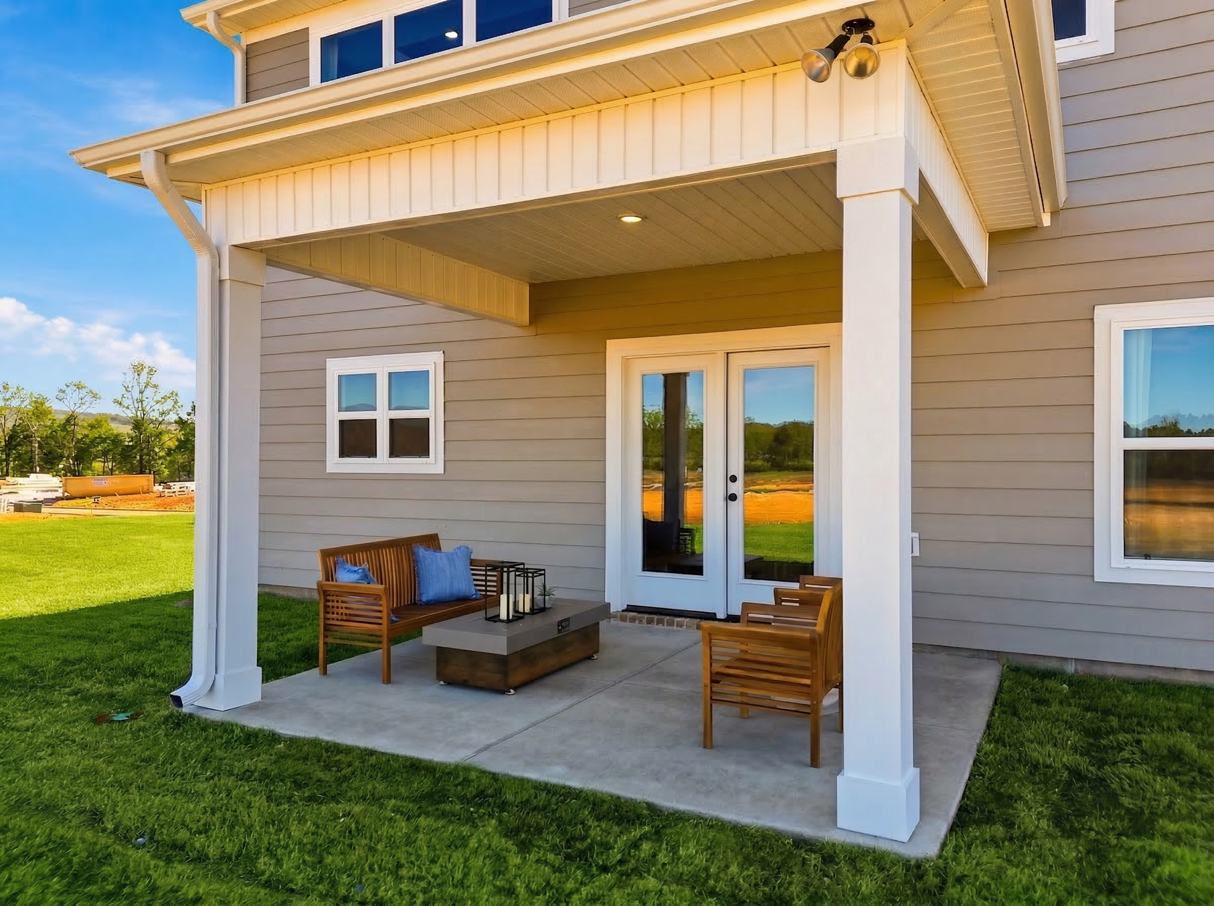 Covered patio at Berry Cove in New Market, Alabama with French doors, wooden chairs, coffee table, and green lawn