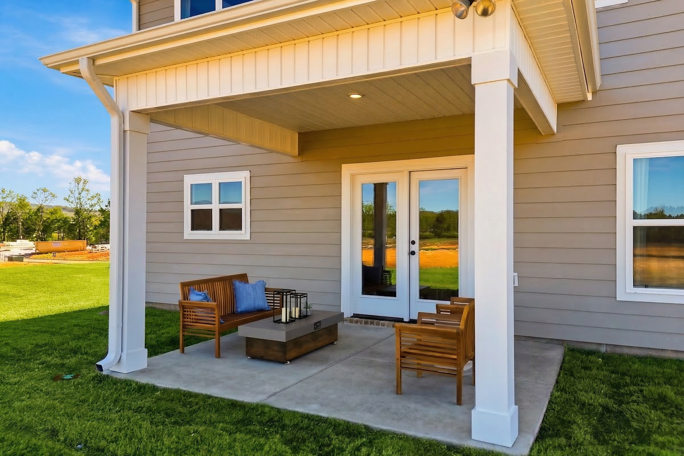 Covered patio at Berry Cove in New Market, Alabama with French doors, wooden chairs, coffee table, and green lawn